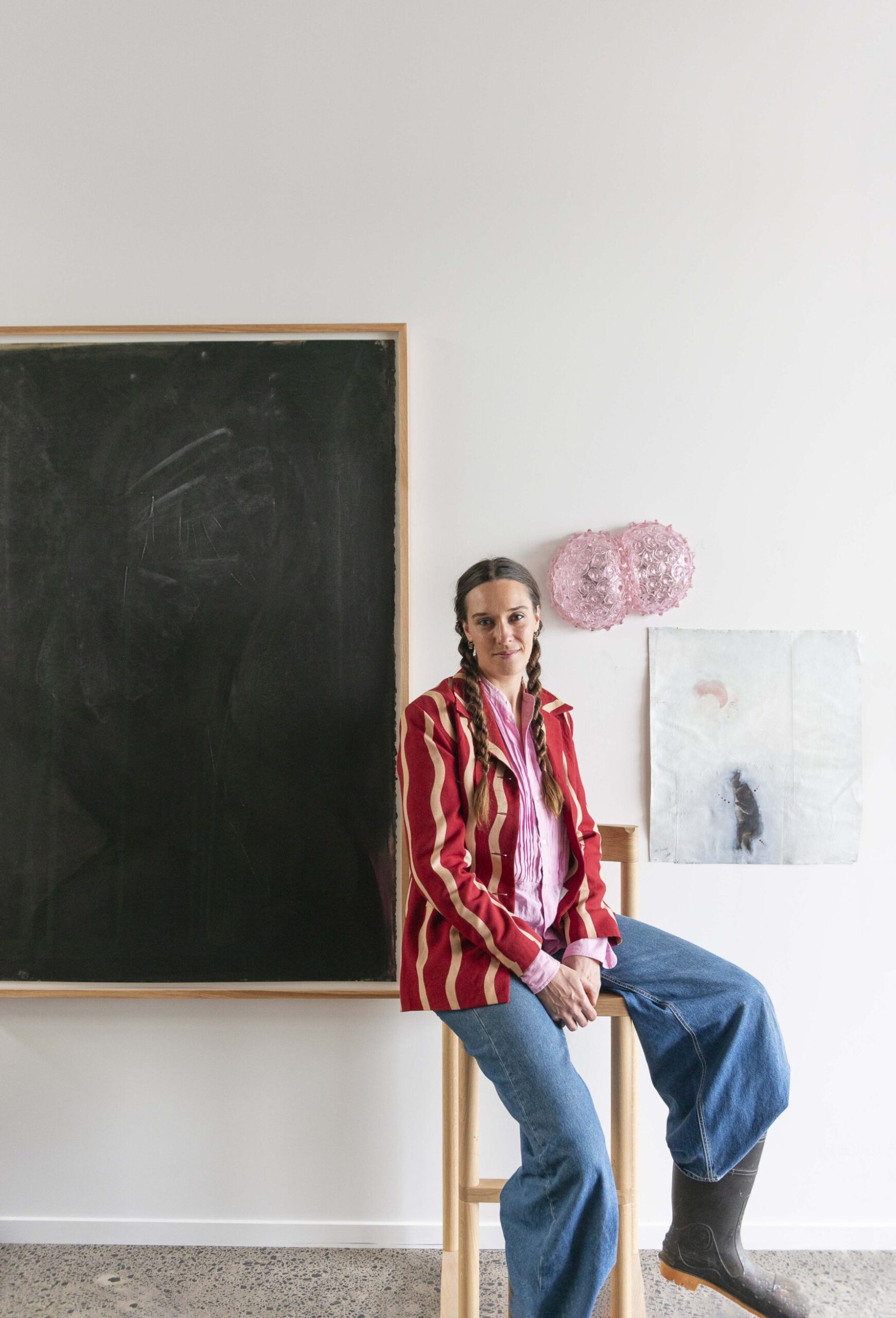 Kate Rutecki sitting on a stool in front of black painting
