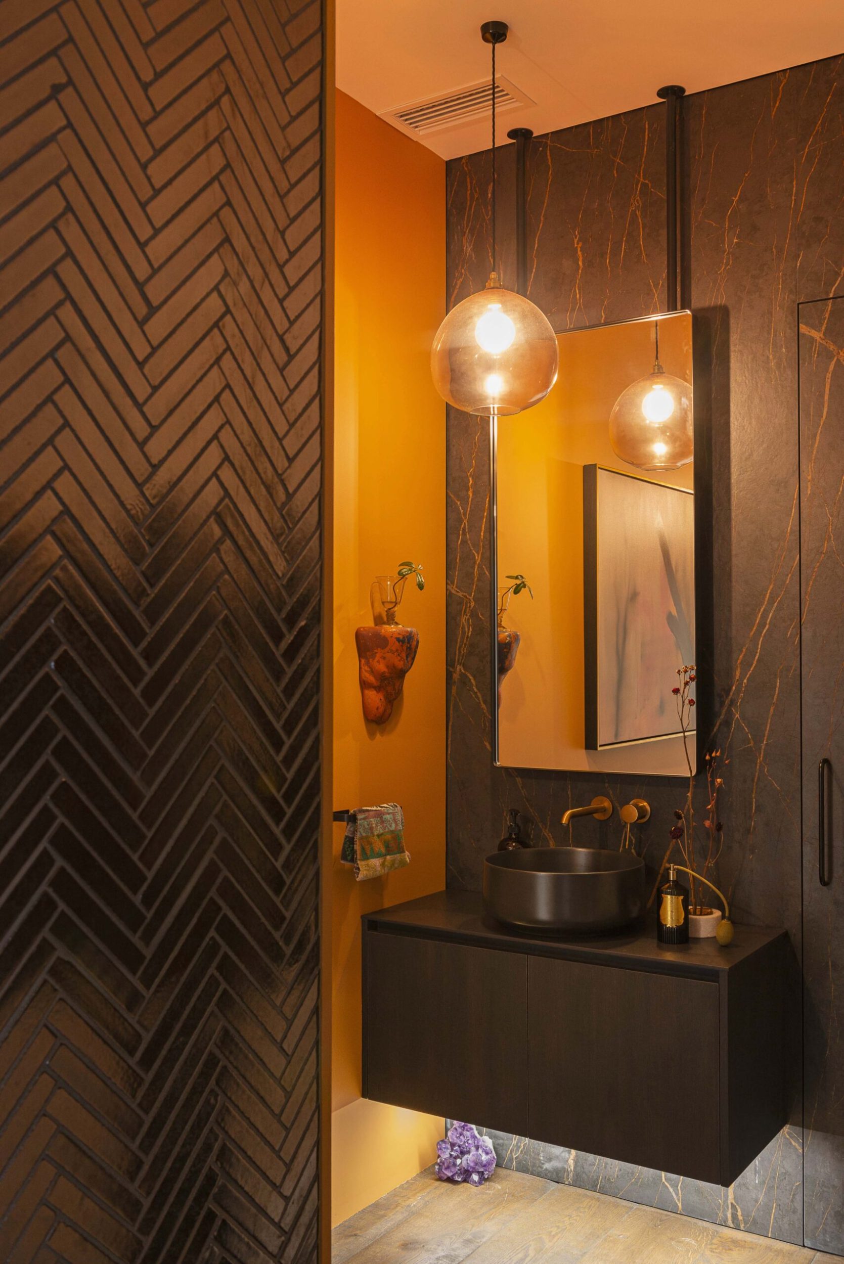 Small powder room with black marble wall and painted orange wall