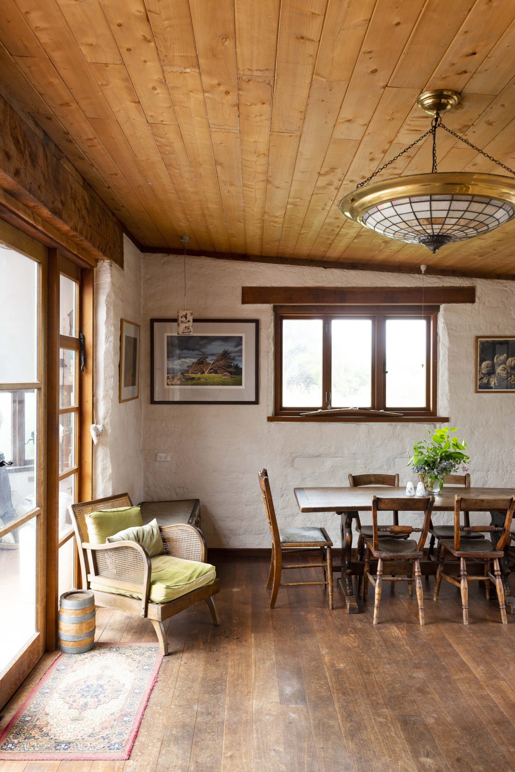 A dining room with white walls, wood ceiling and wood floor with a dark wood dining table and chairs