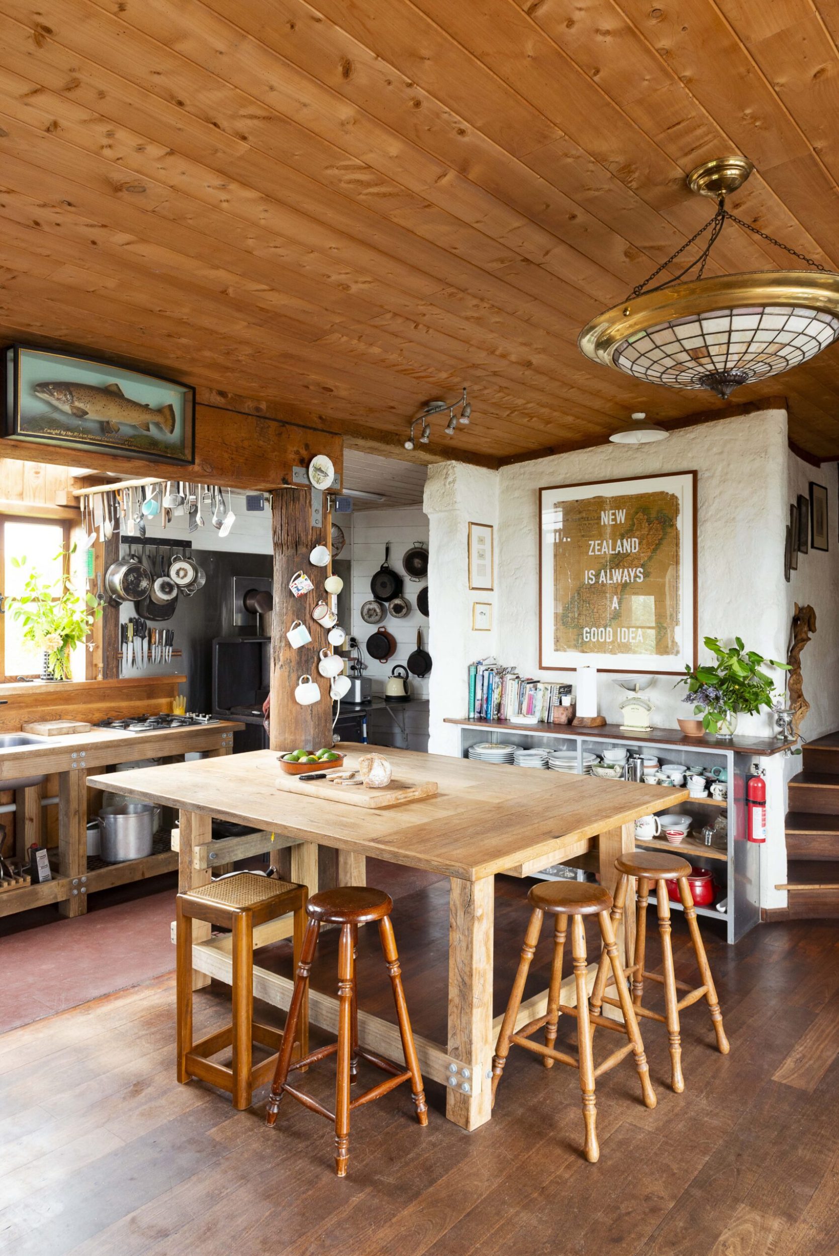 A kitchen with wood floors, wood ceiling panels, white walls and a wood kitchen island