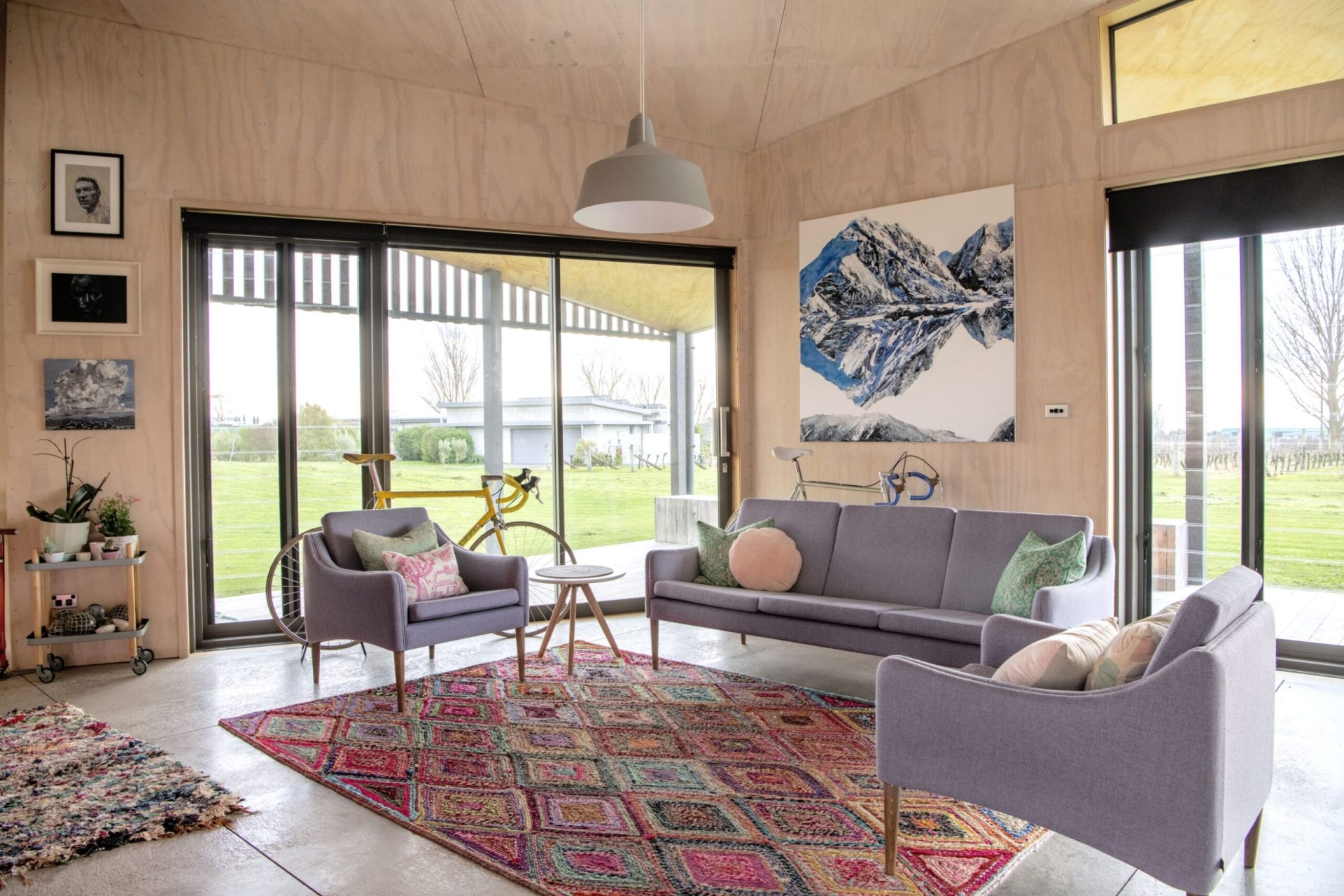 Living room with wood panel walls, red geometric rug and grey couches 