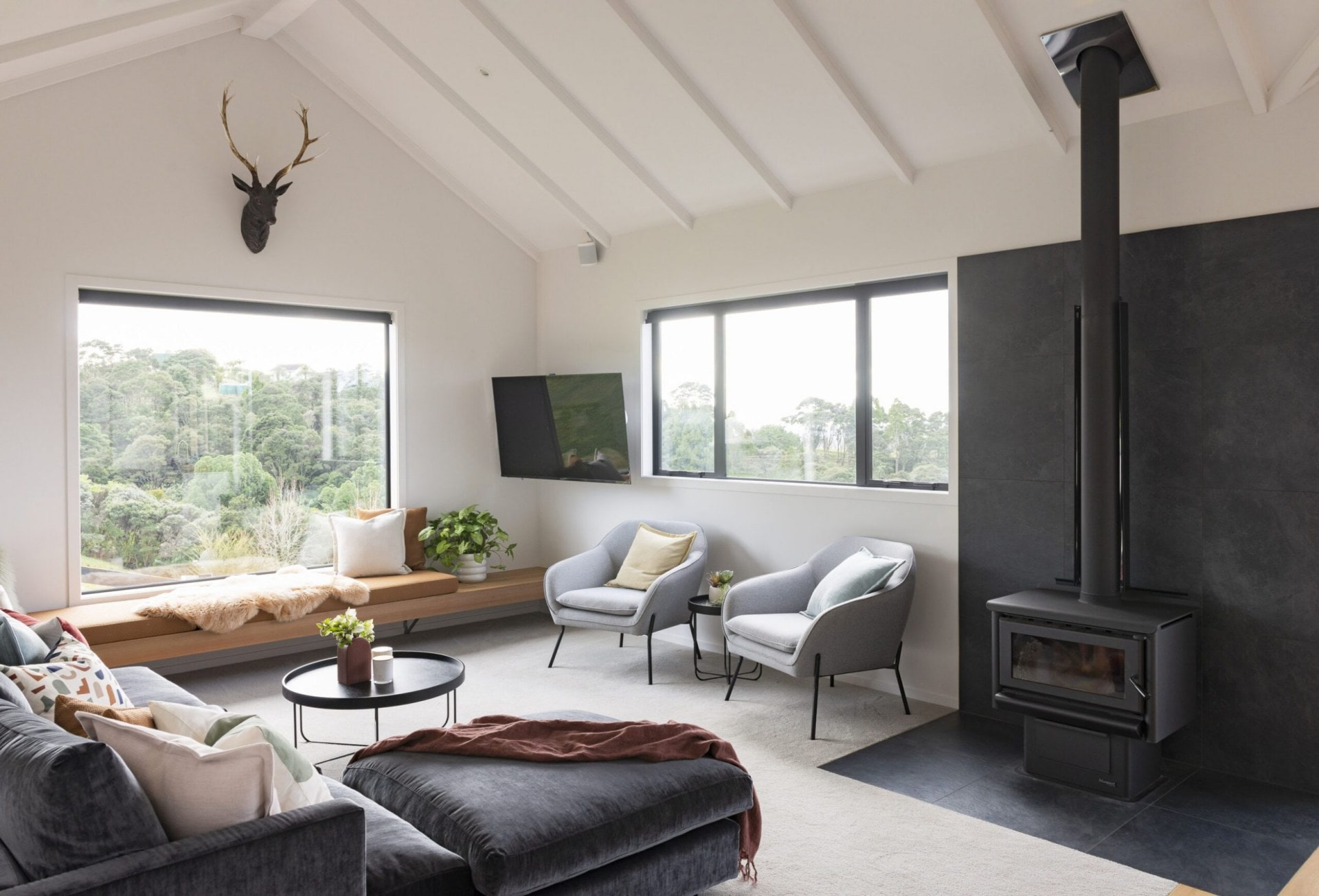 Living room with grey couches and chair, fire place and window seat