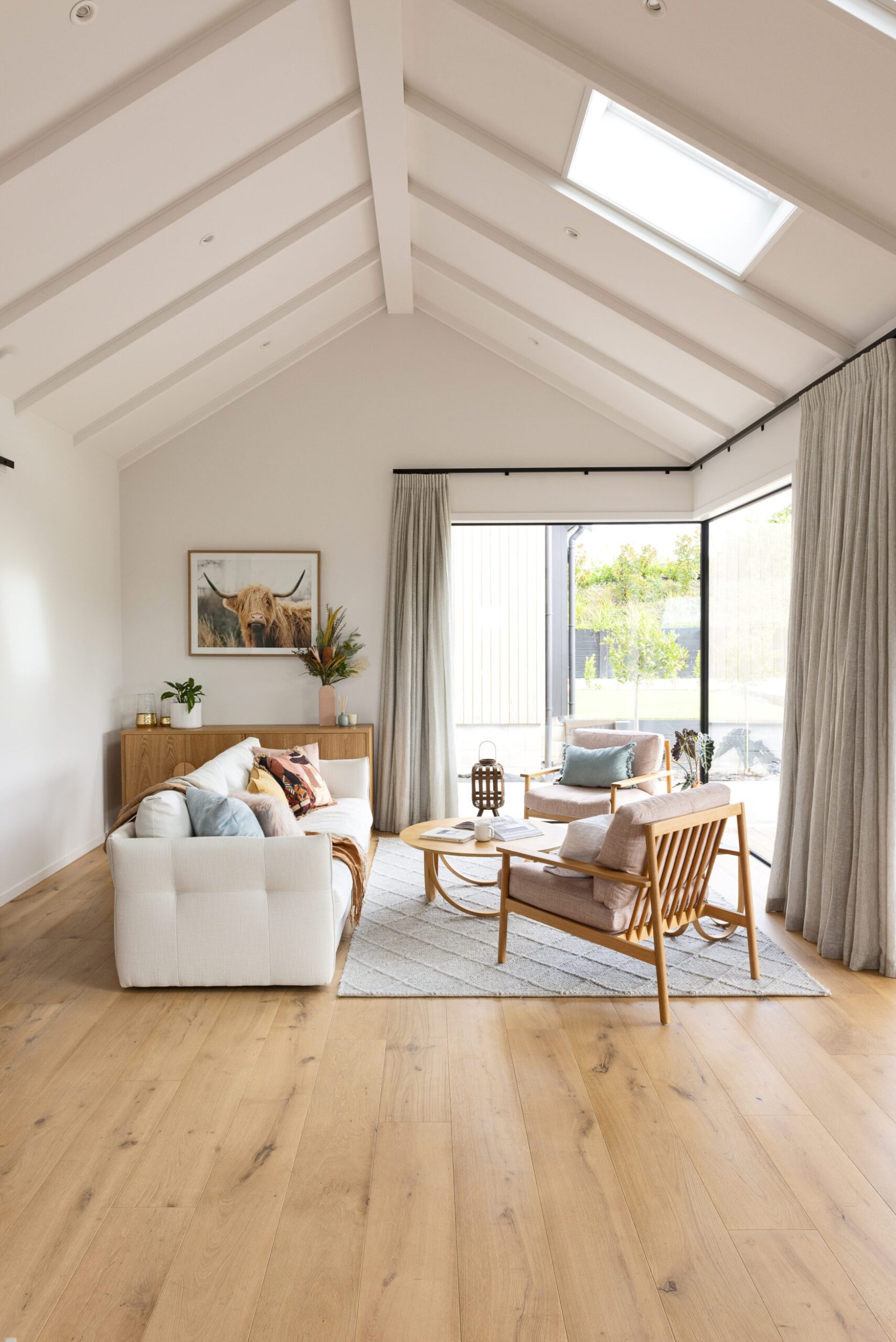 A living room with cathedral ceilings, a white couch and a ceiling light