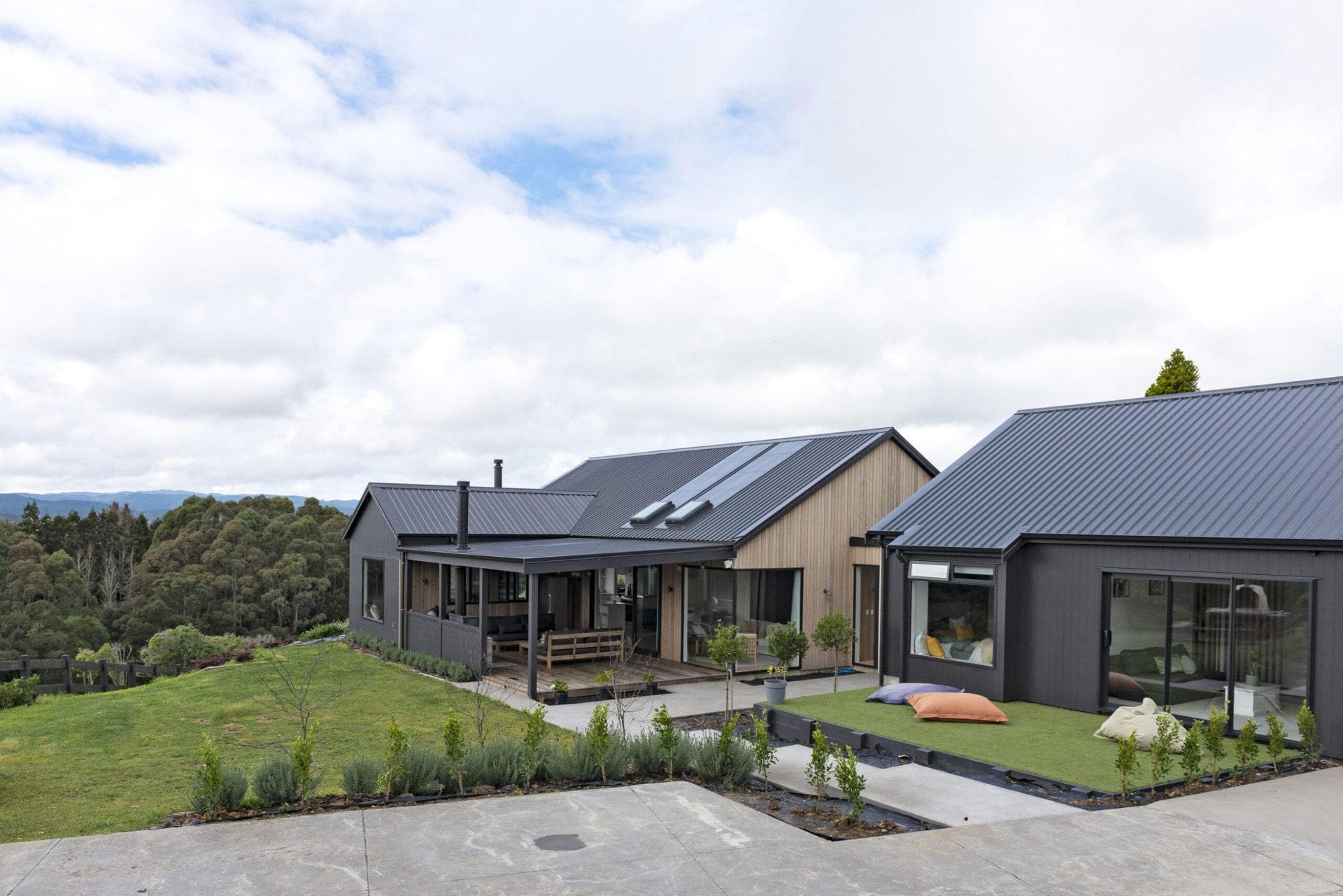 Exterior of two black barn houses with gabled roofs and cedar cladding