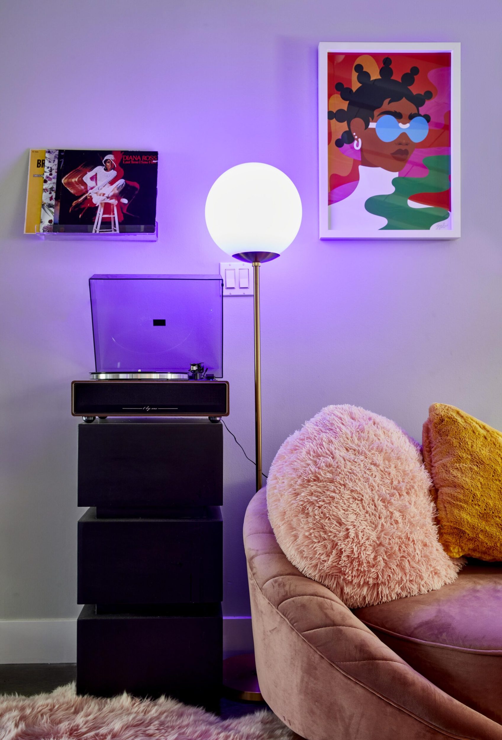 Parris Goebel living room with hanging art, a blue neon lamp, pink velvet couch 