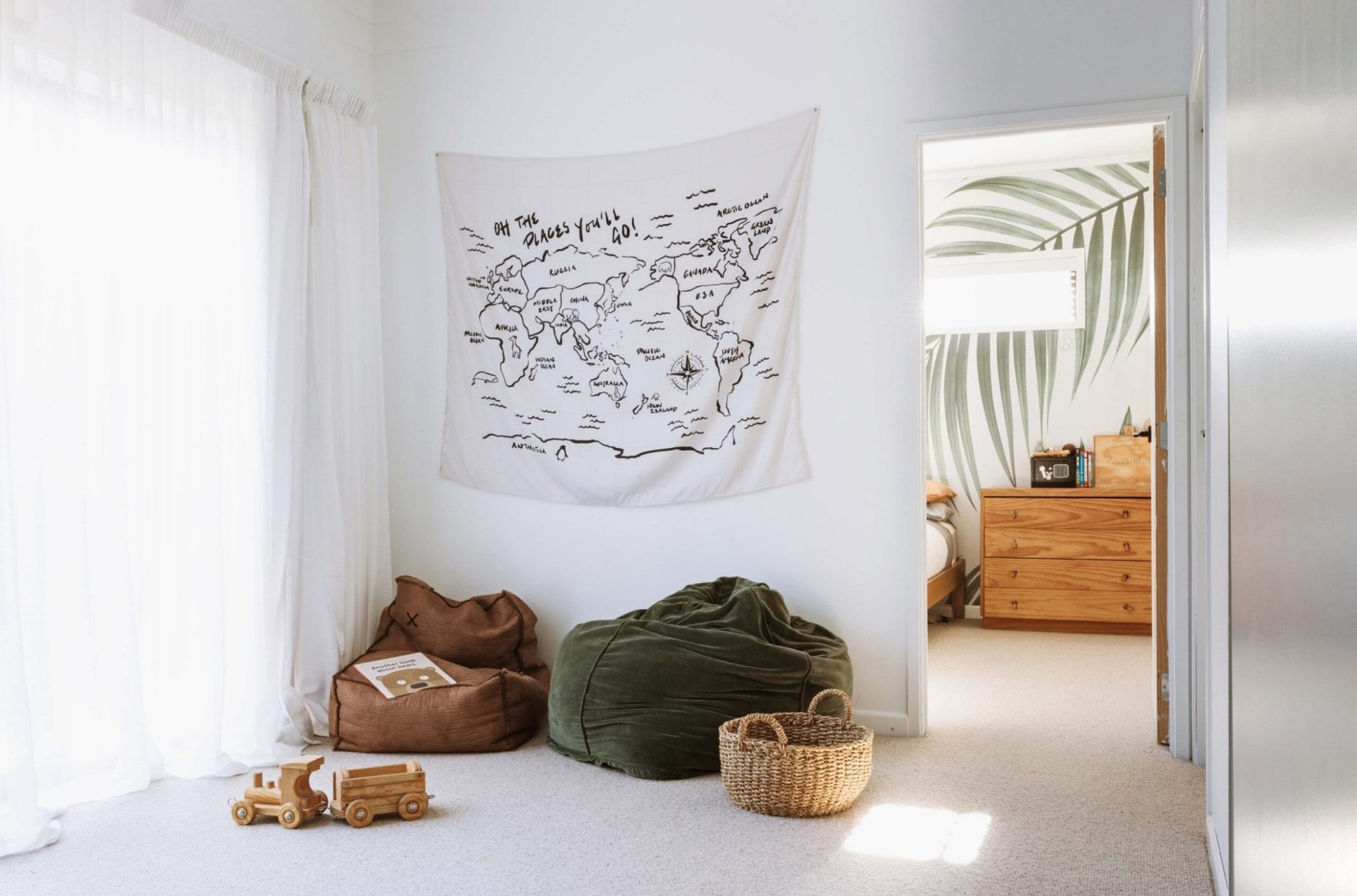 rumpus room, with two bean bags, a wall hanging, and a door opening to an added bedroom