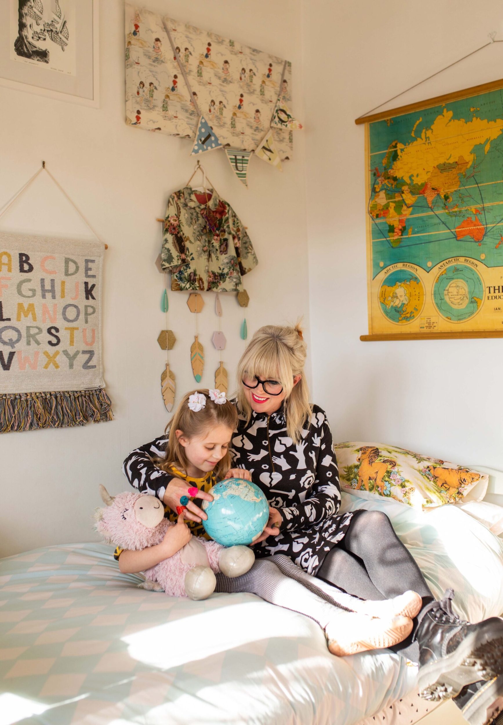 Rachel Stone and her daughter Juno sitting on her bed with art on the walls