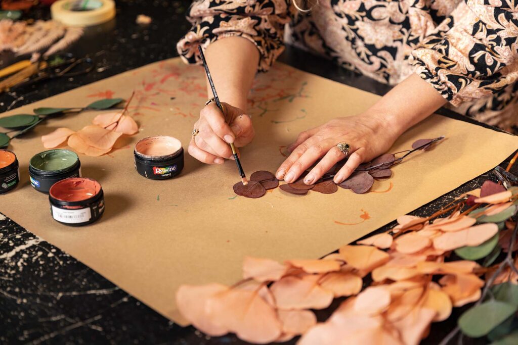 Using a paint brush Georgie paints some leaves
