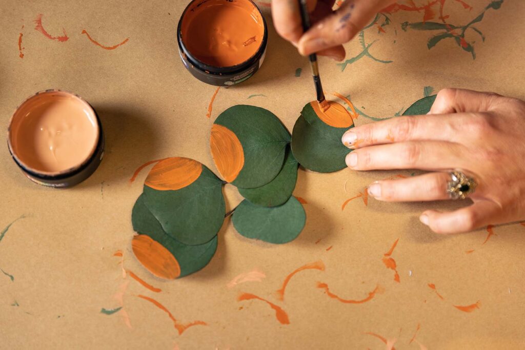 Orange paint being painted on eucalyptus leaves
