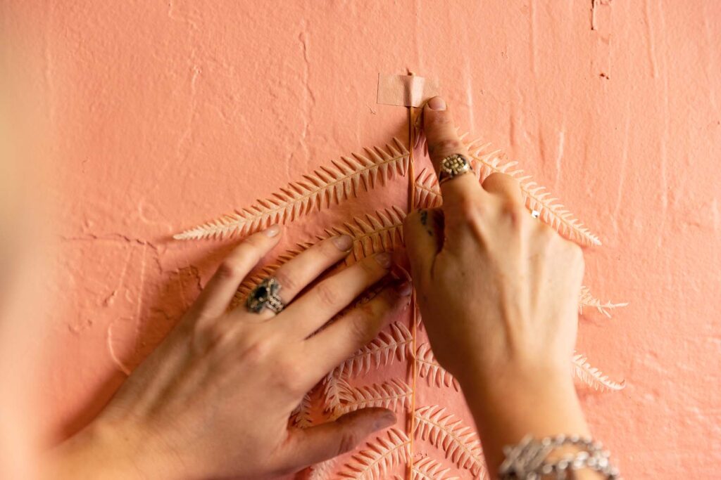 Taping a painted leaf to the wall