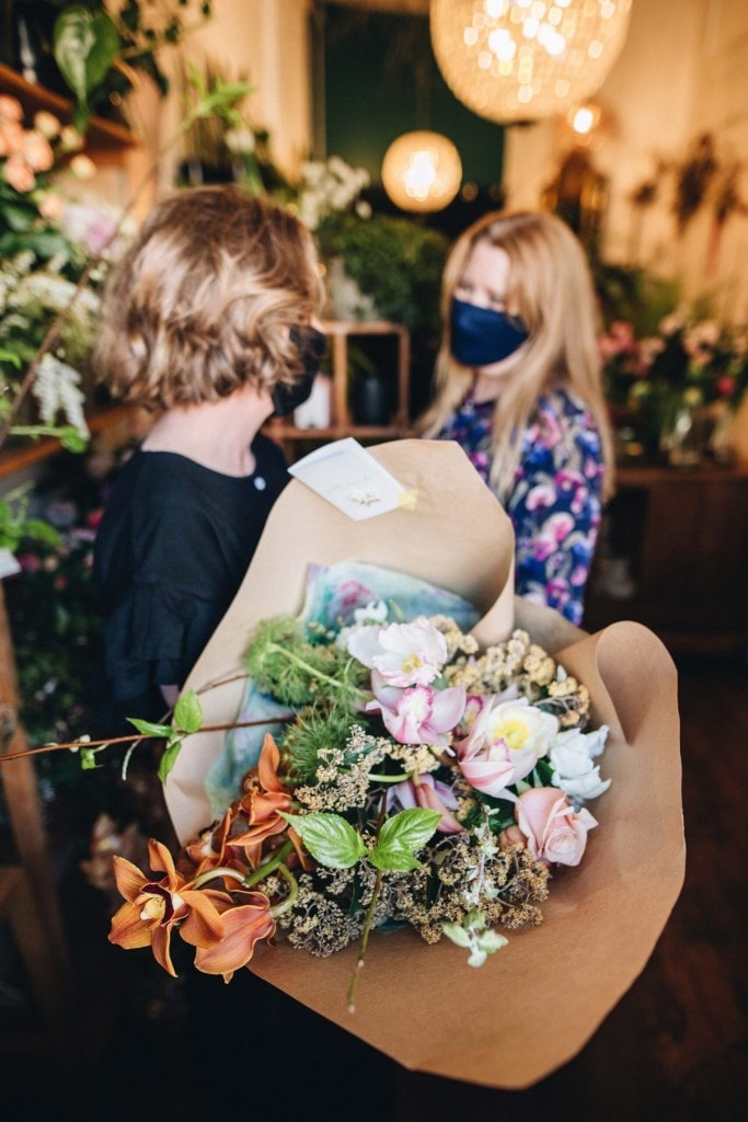 Yvette Edwards holding a floral arrangement in brown paper