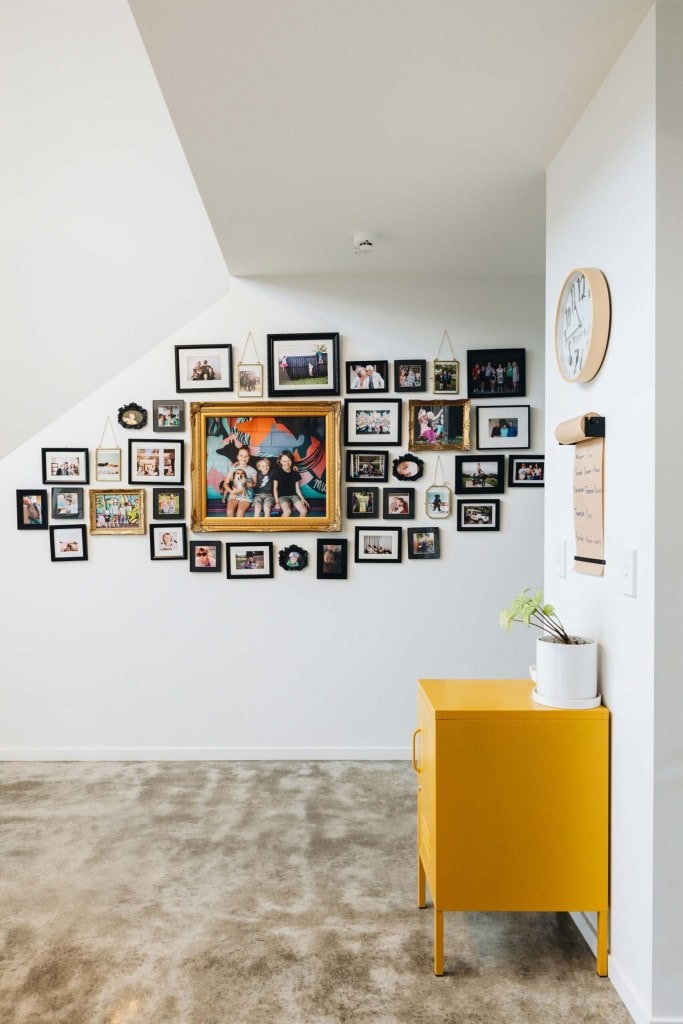 A gallery wall of family photographs hanging on a white wall