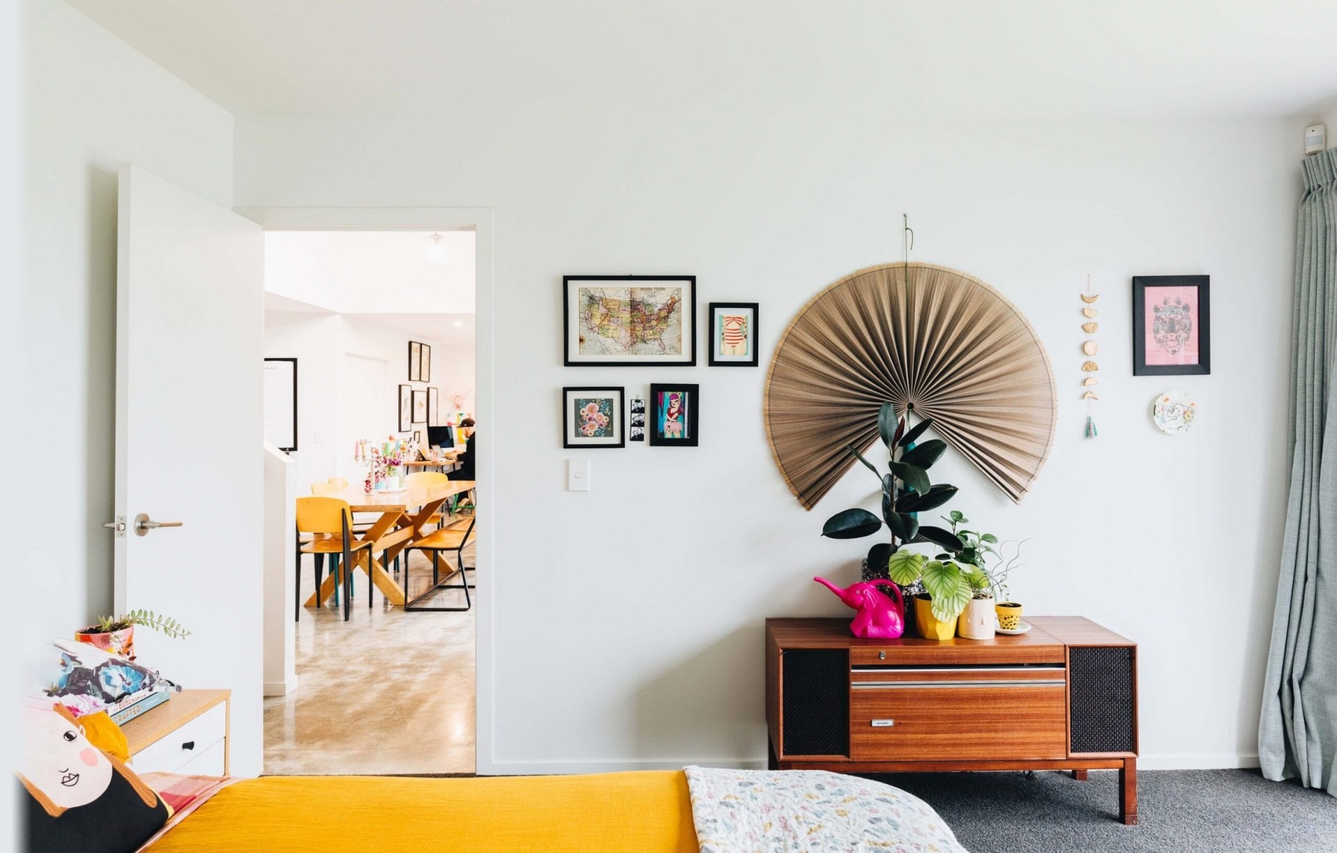 The master bedroom with various art on the wall above a small sideboard