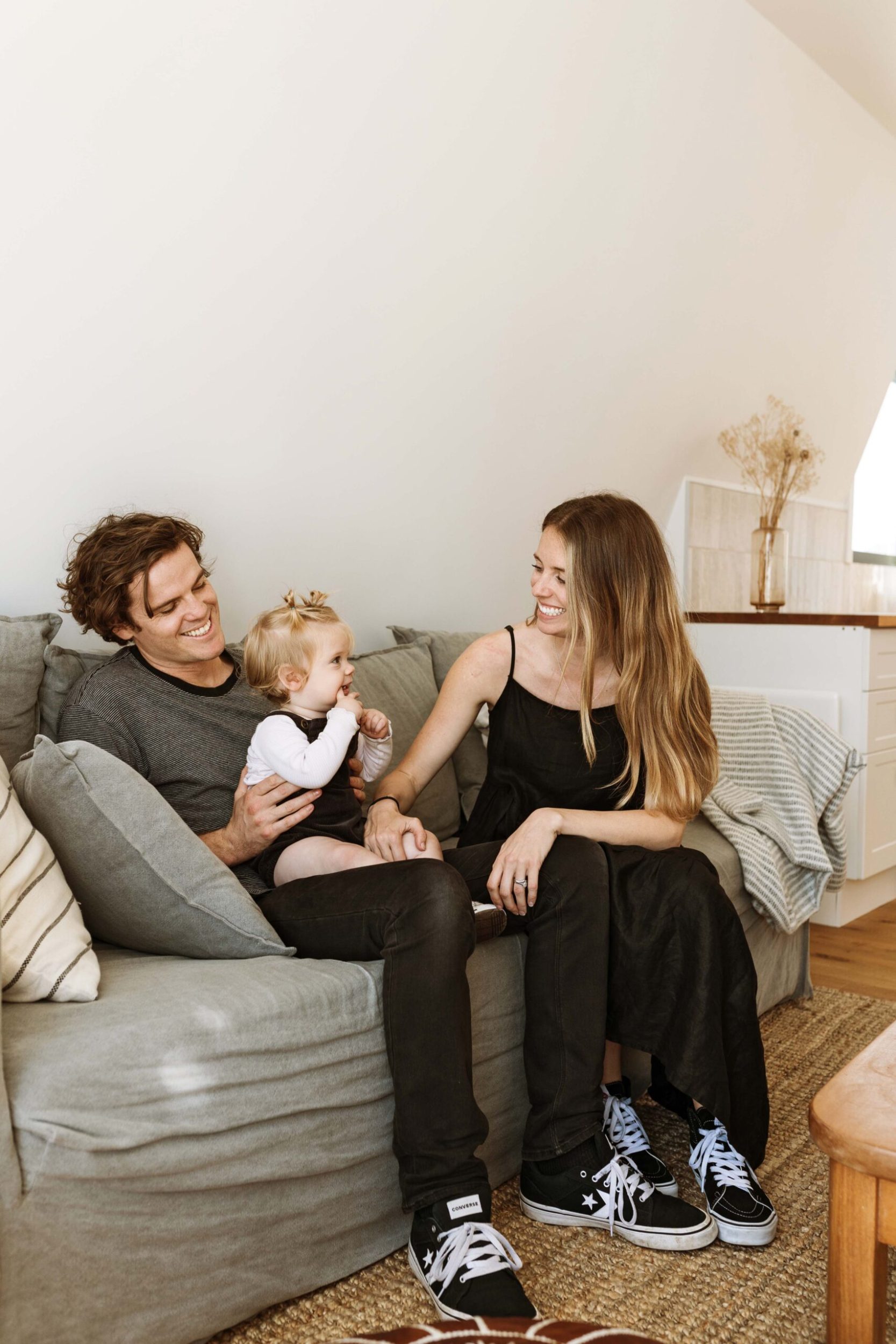 Laura and Andrew Priestley, sitting on a grey couch with their daughter Elle