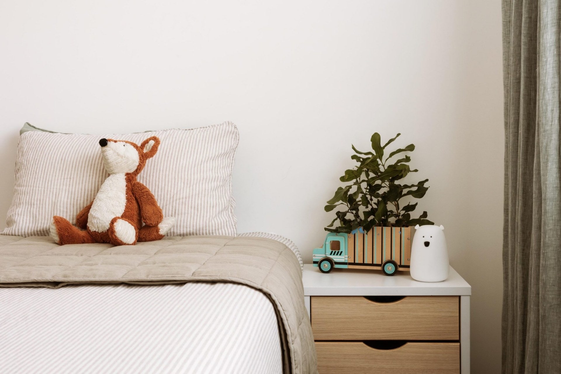 Kit's bedroom with stripy linen and a wood and white bedside table