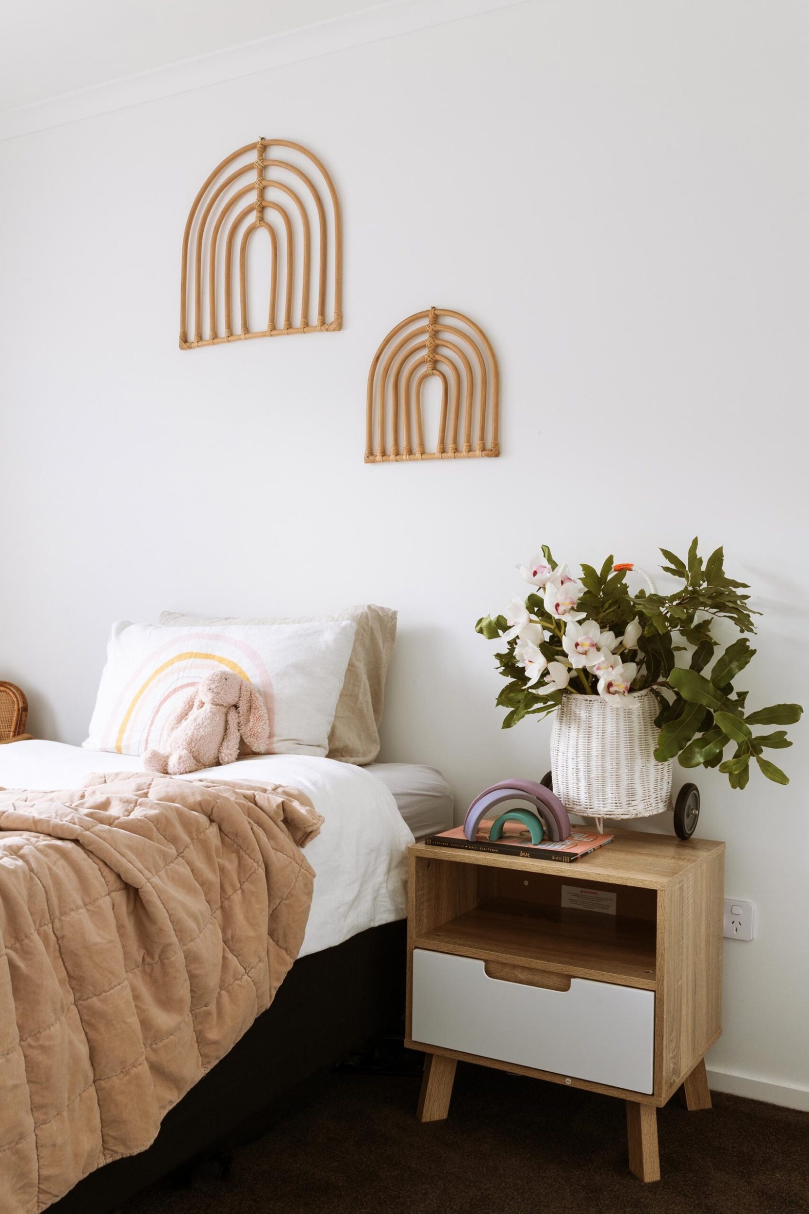 Pepper's bedroom with white walls and two rainbow wall hangings