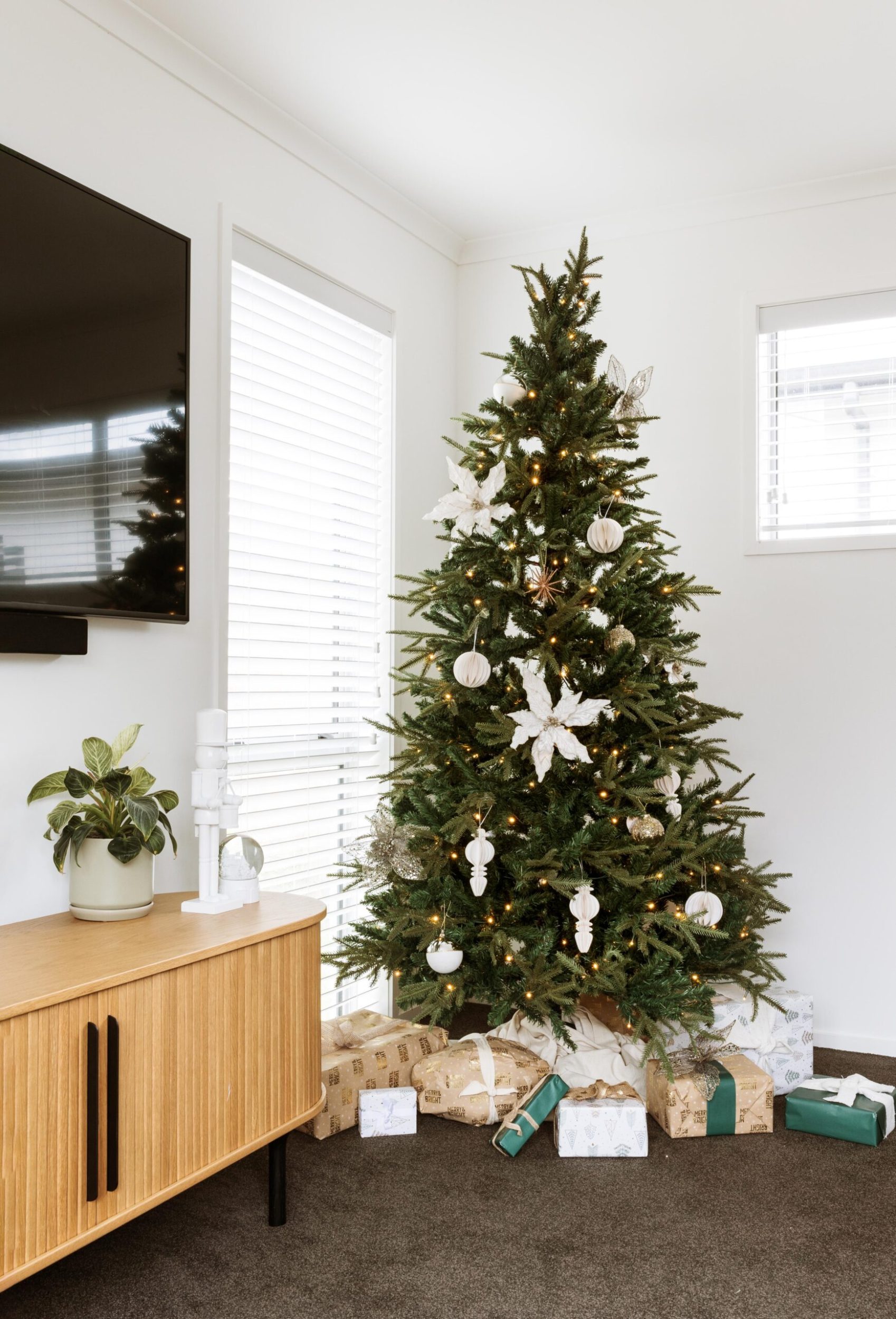 Cherie's Christmas tree next to the tv cabinet that is a light wood and has a curved edge