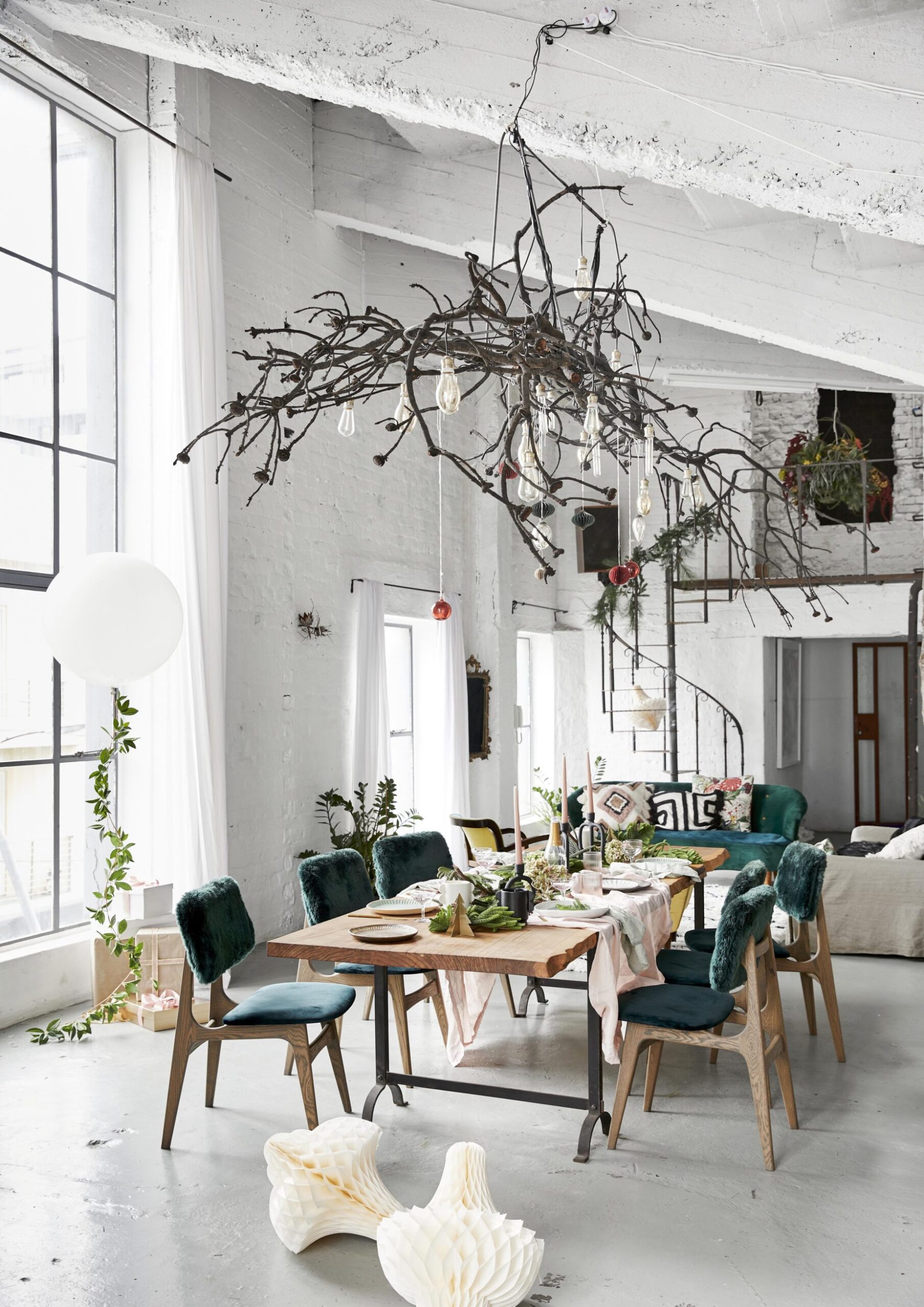 a branch garland hanging from the ceiling above a timber table