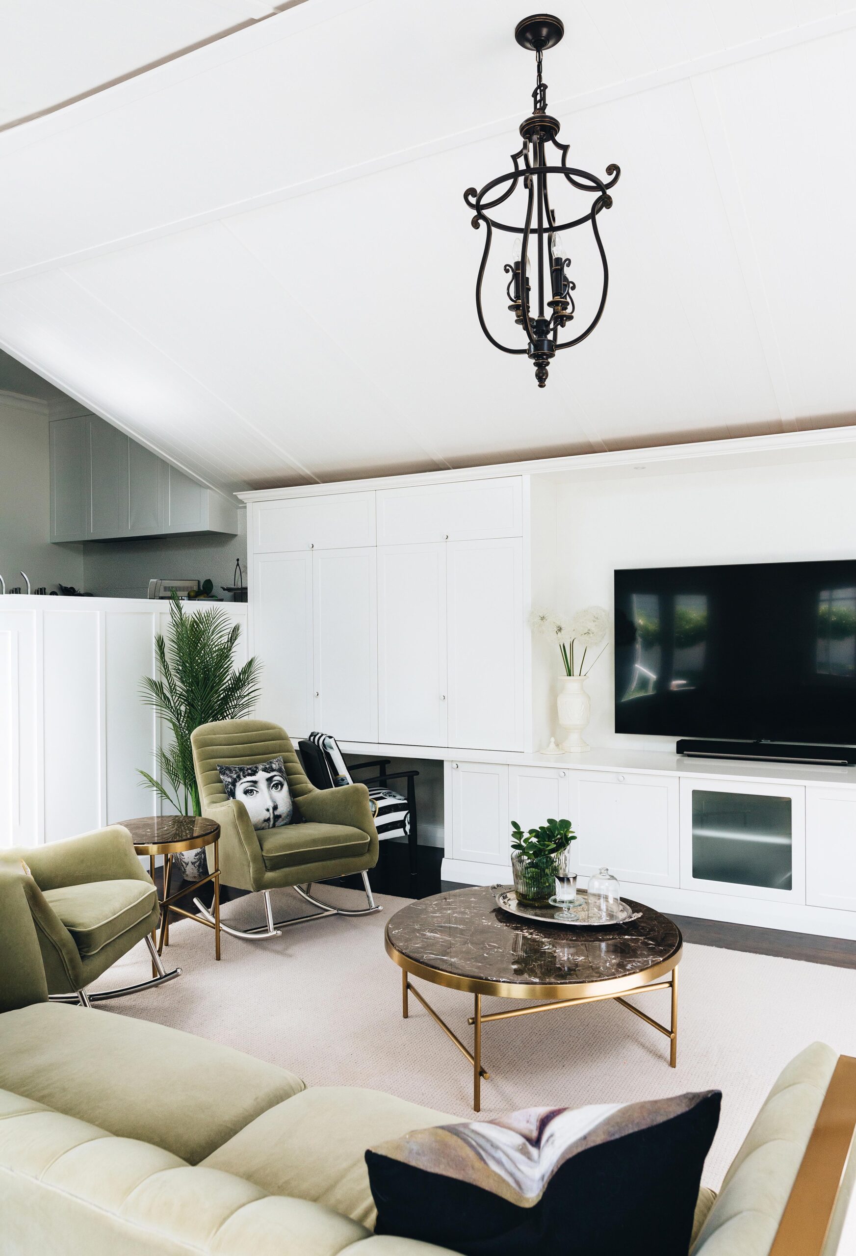 living room with white walls and beige couches, there are two olive arm chairs in the left