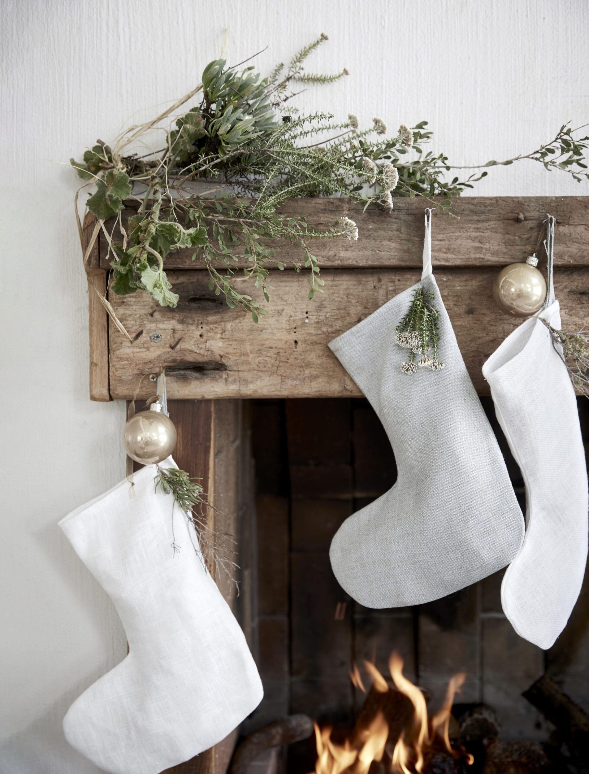 white stockings hanging from a rustic wooden mantle