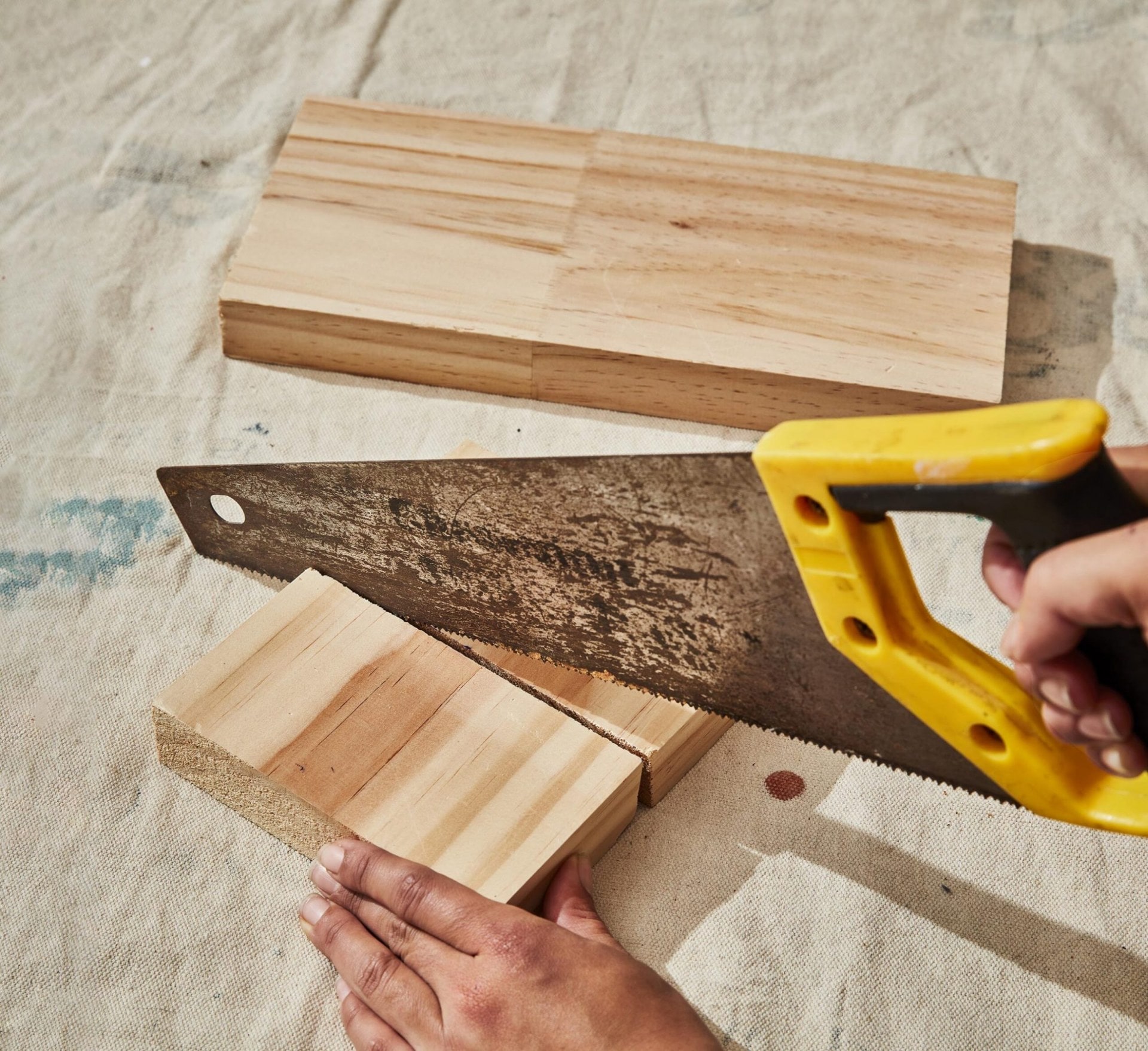 A yellow saw sawing a piece of timber