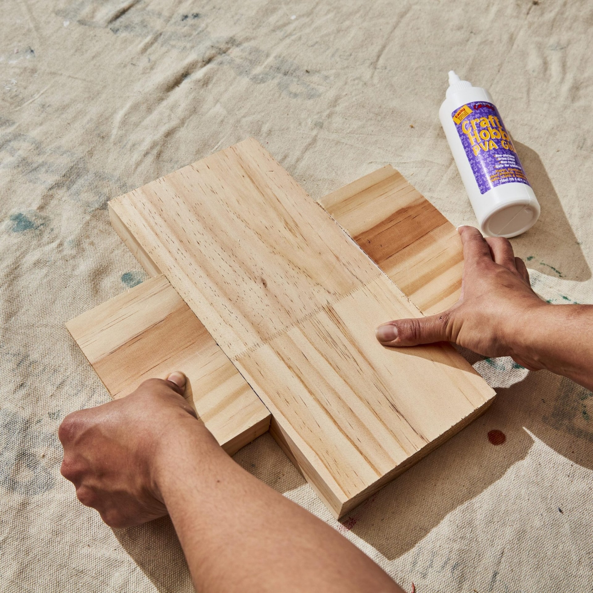 hands glueing two pieces of wood together