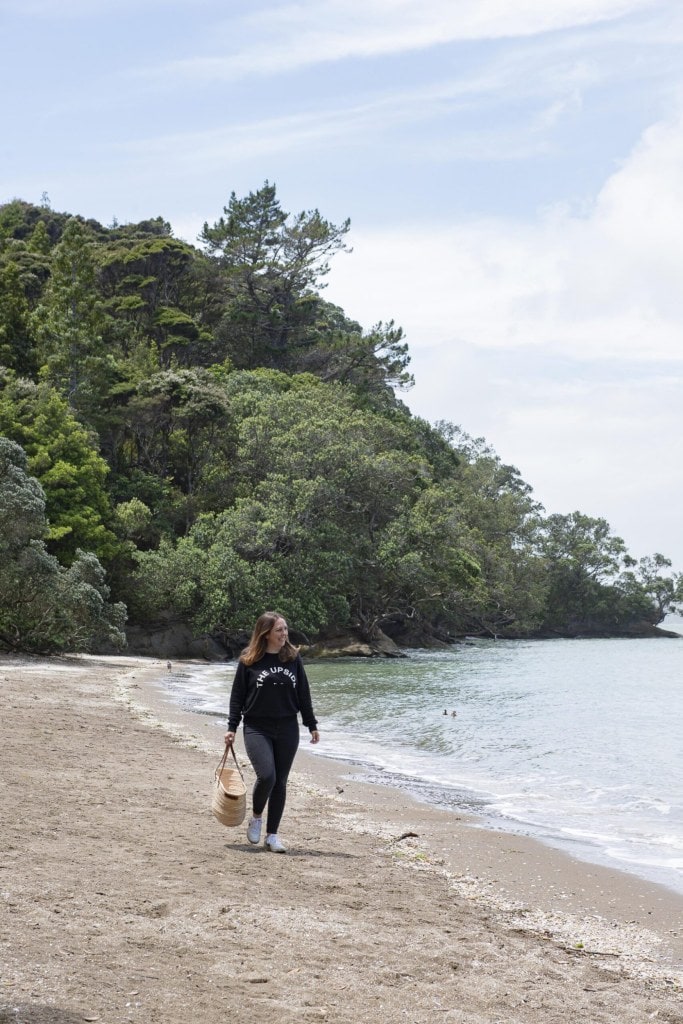 Claudia Zinzan walking down a beach carrying a bag