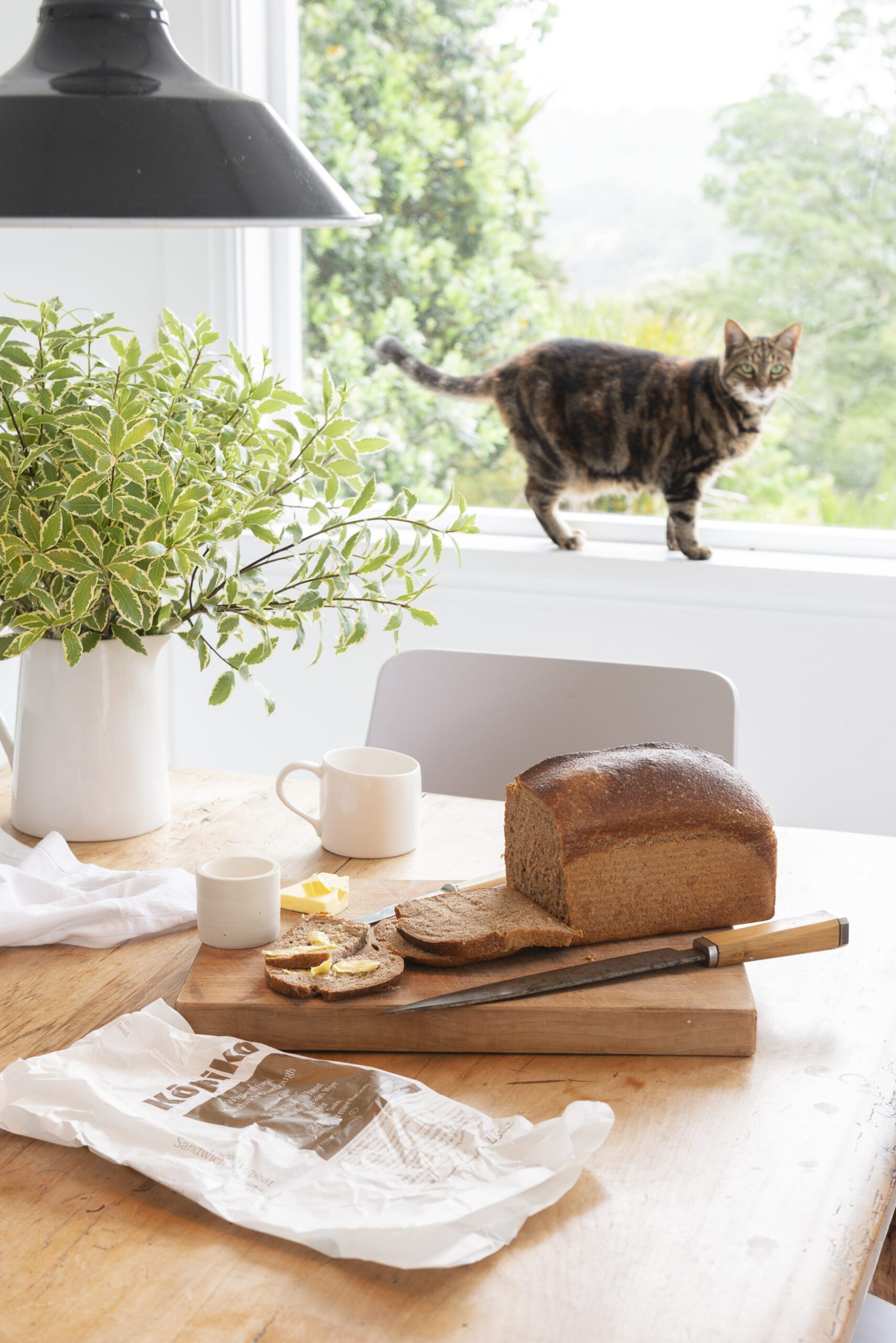 Sliced loaf on dining room table with cat in the background