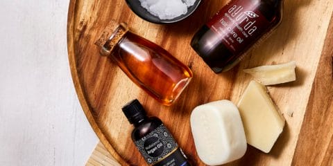 A collection of natural hair products on a round wooden board