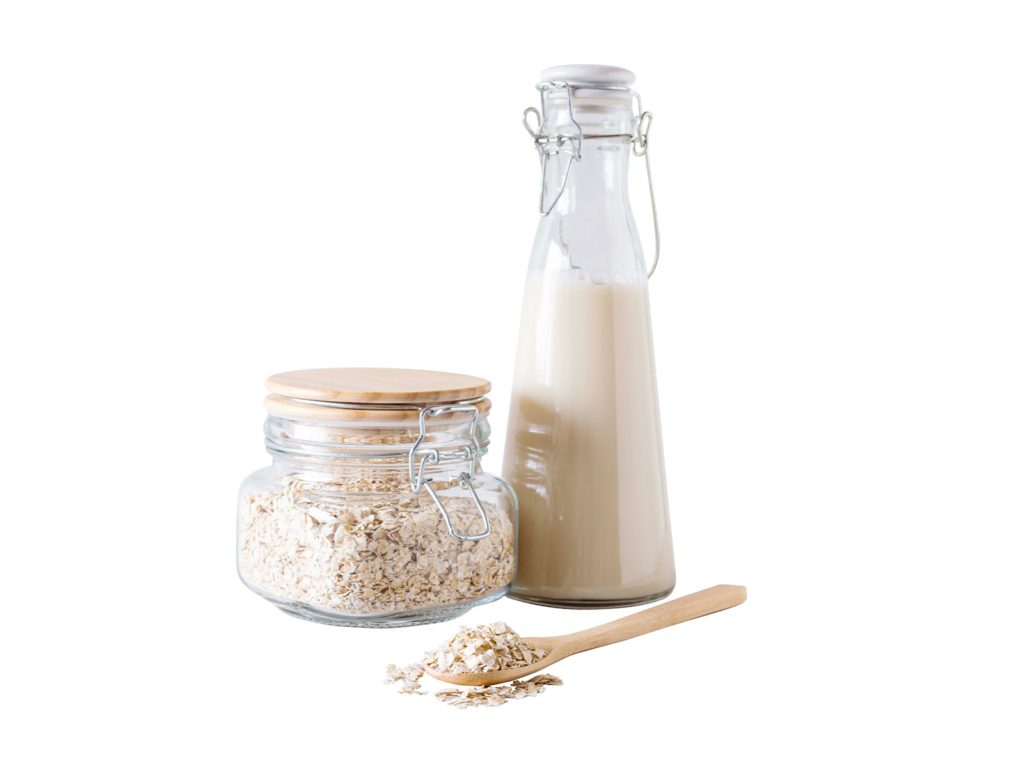 a jar of oats next to a bottle of oat milk