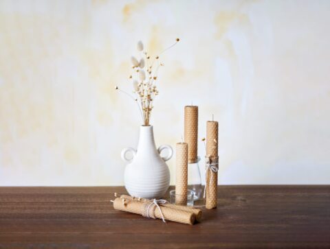 A white vase surrounded by honey candles