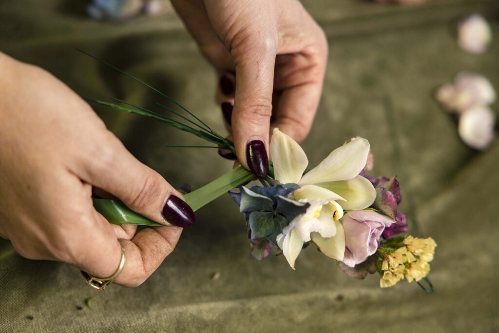 Hands using green tape to wrap flowers onto a wire crown