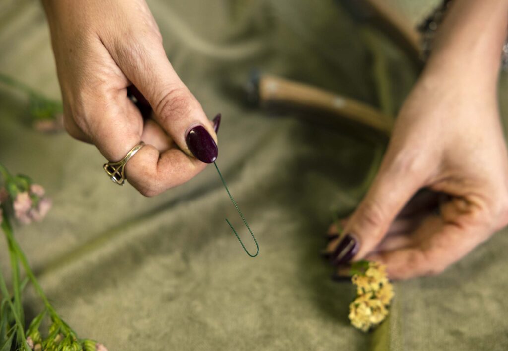 hand holding green wire bent in a hook shape