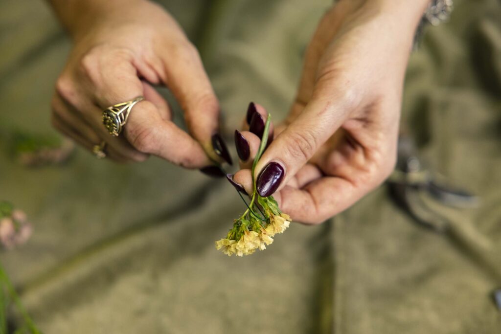 Hands threading wire around yellow flower