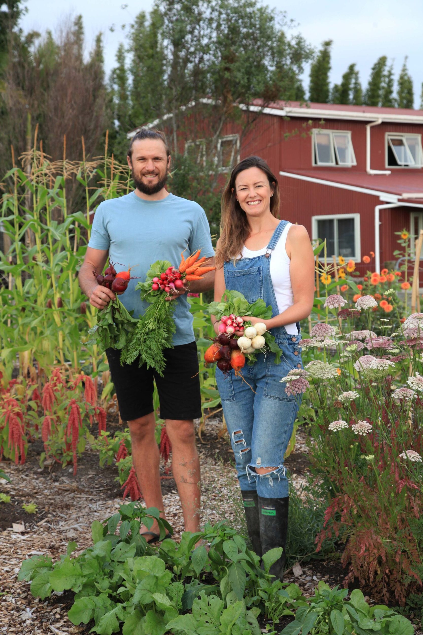 Jen and Gus Ross standing in vege garden holding vegetables