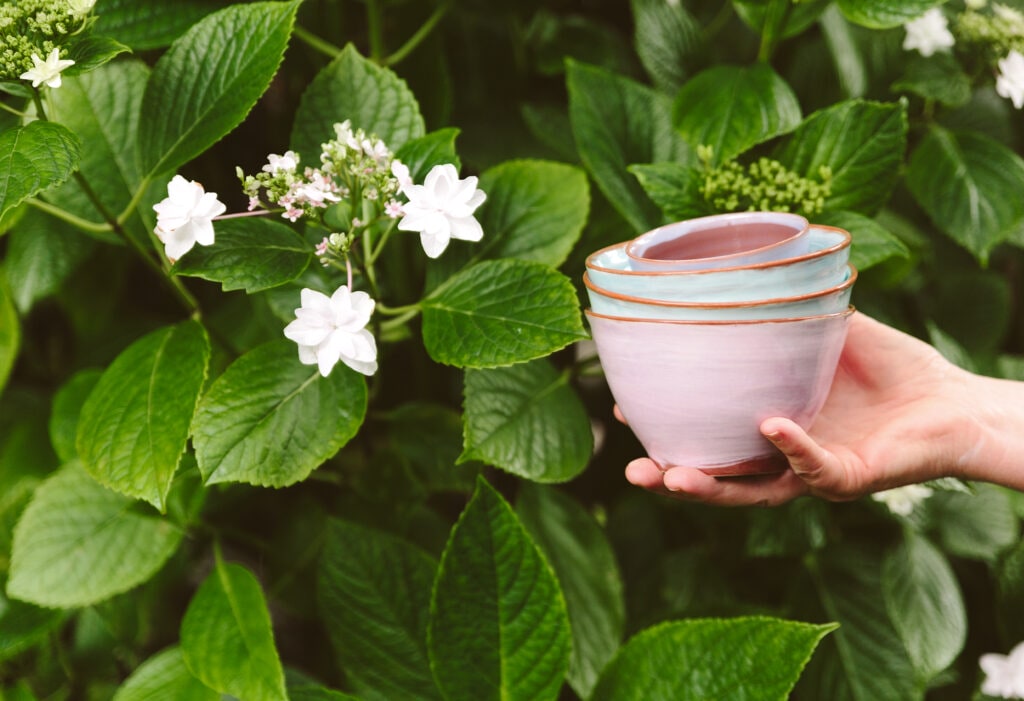 Kathryn Smythe's pottery held against flower bush