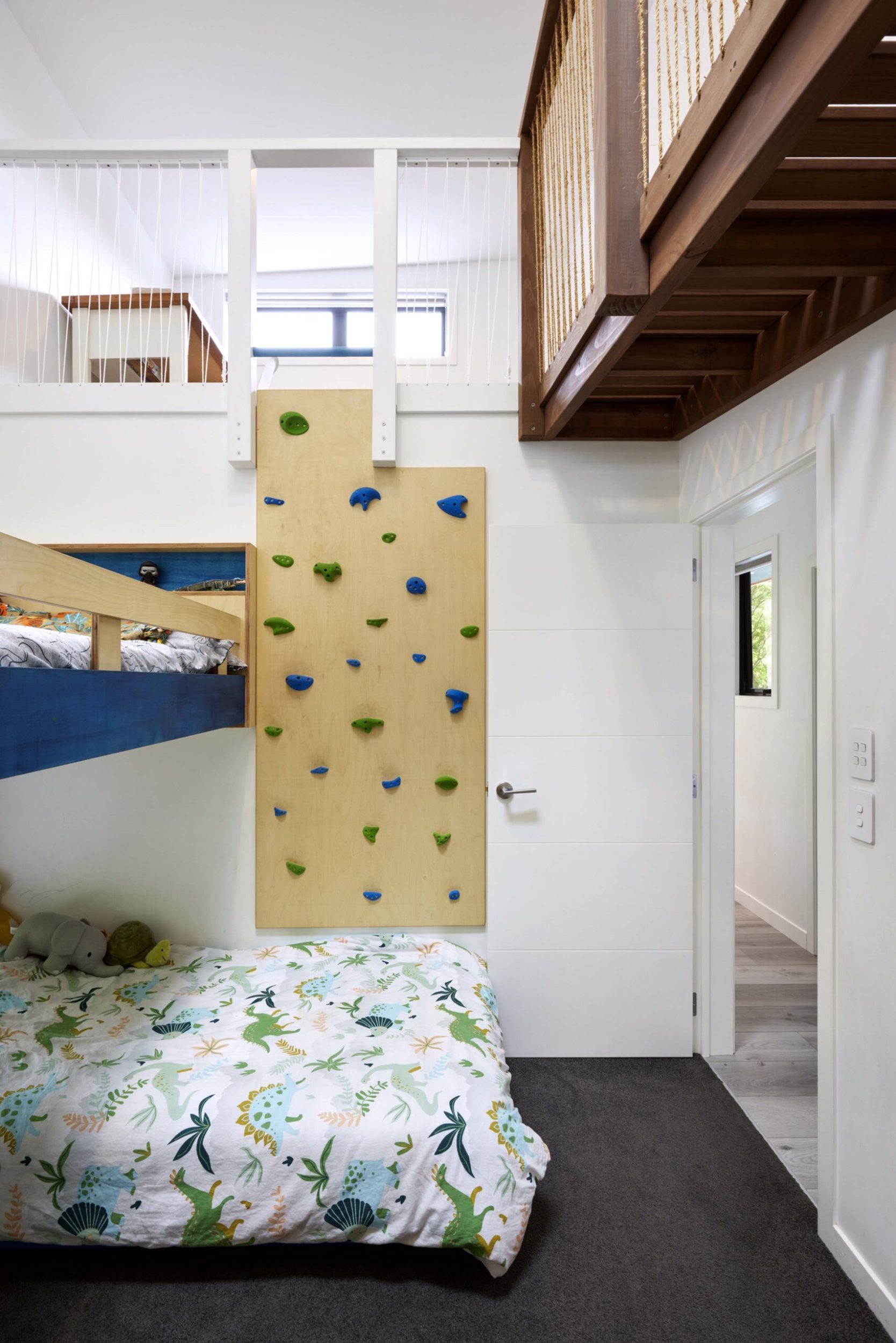 A kids bedroom with a rock climbing wall reaching to a second story