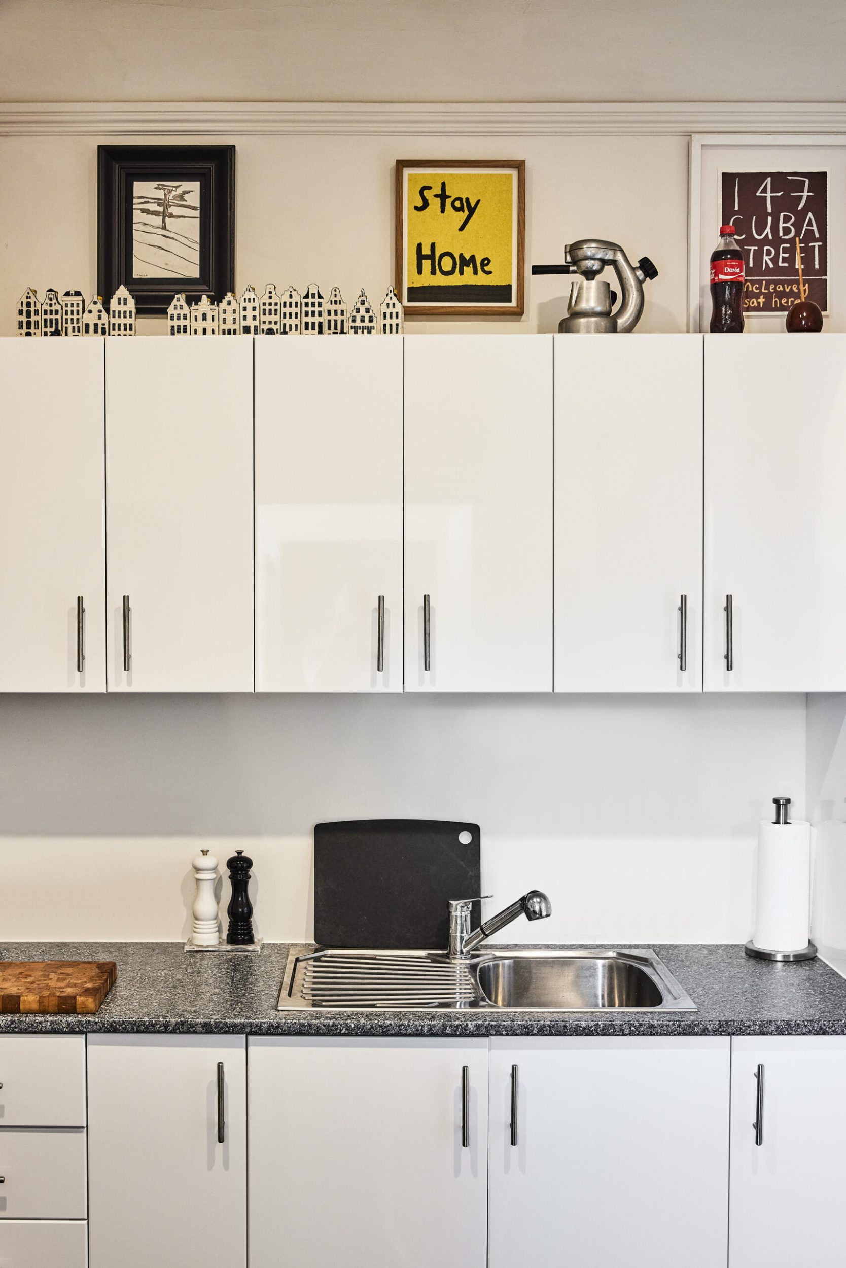 A small kitchen with white cabinets and grey benchtops 