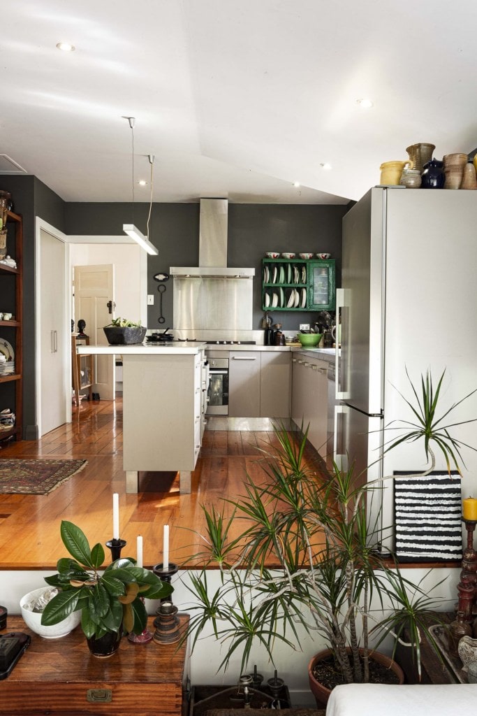 A kitchen with sloping white ceilings and black walls and plants