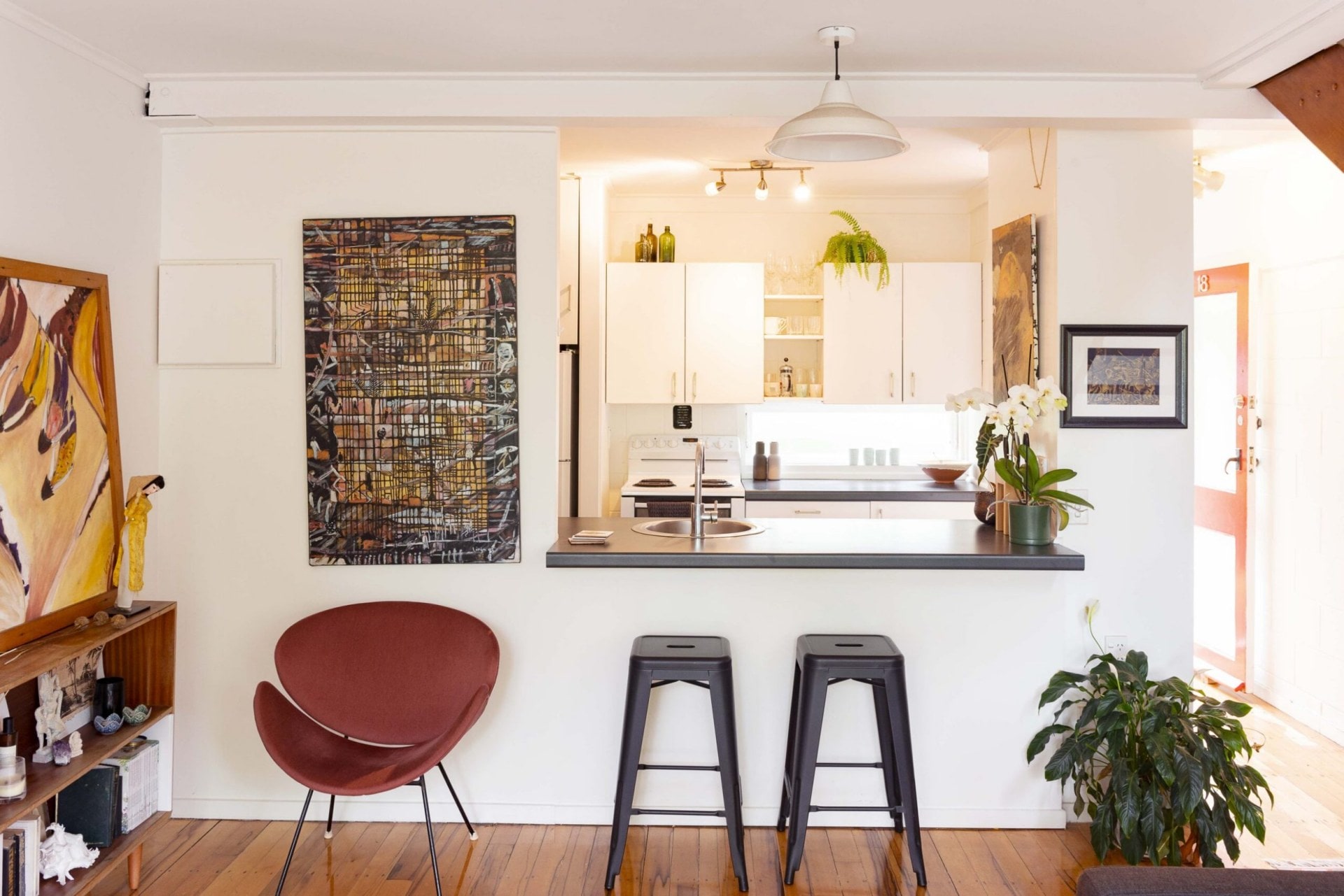 Kitchen with black chairs and black marble surrounded with green plants