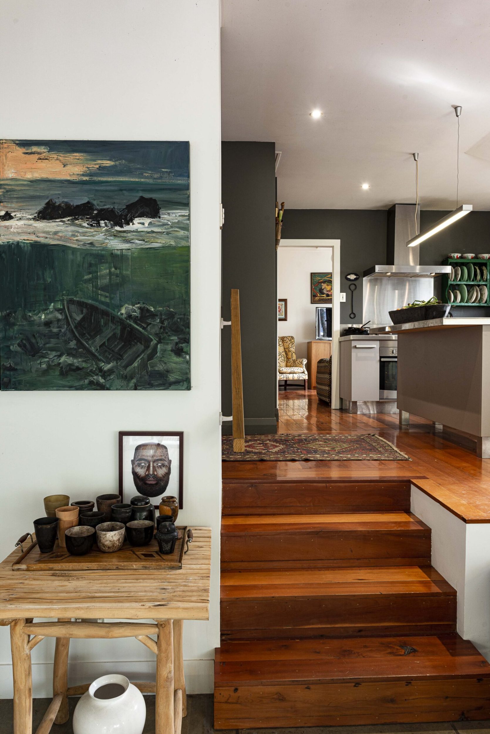 Polished mataī wooden stairs leading up to a black kitchen