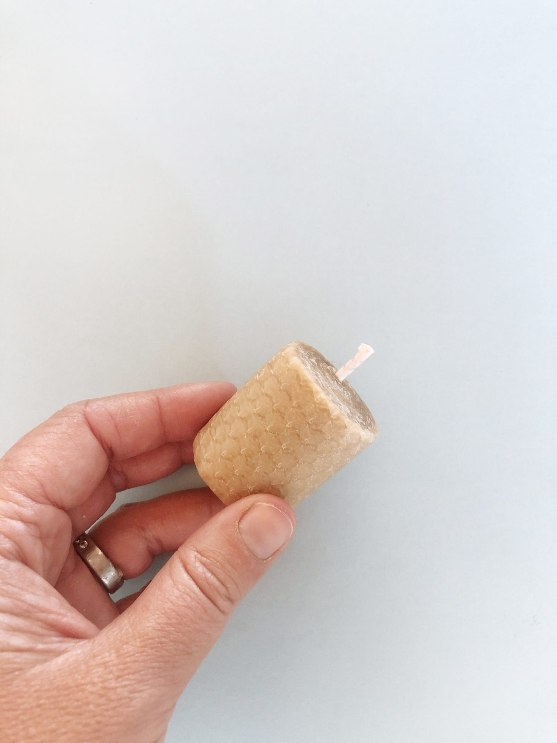 Hand holding short bees wax candle