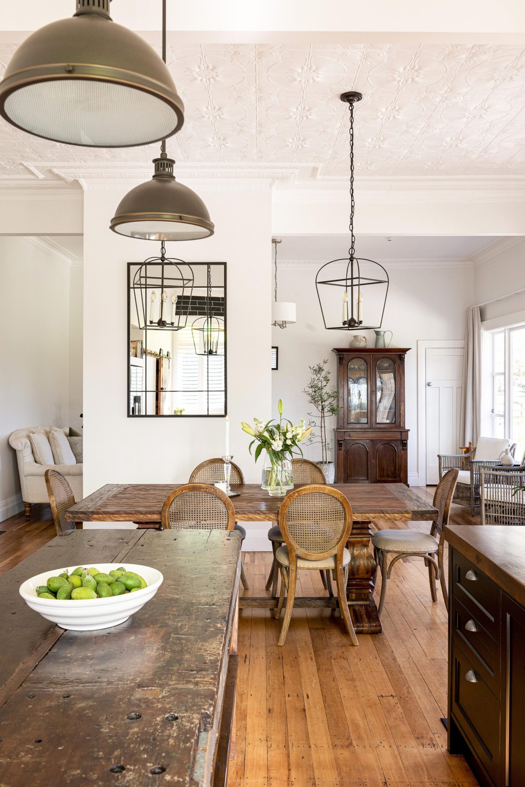A country farmhouse kitchen with vintage tables, white walls and polished wood floors