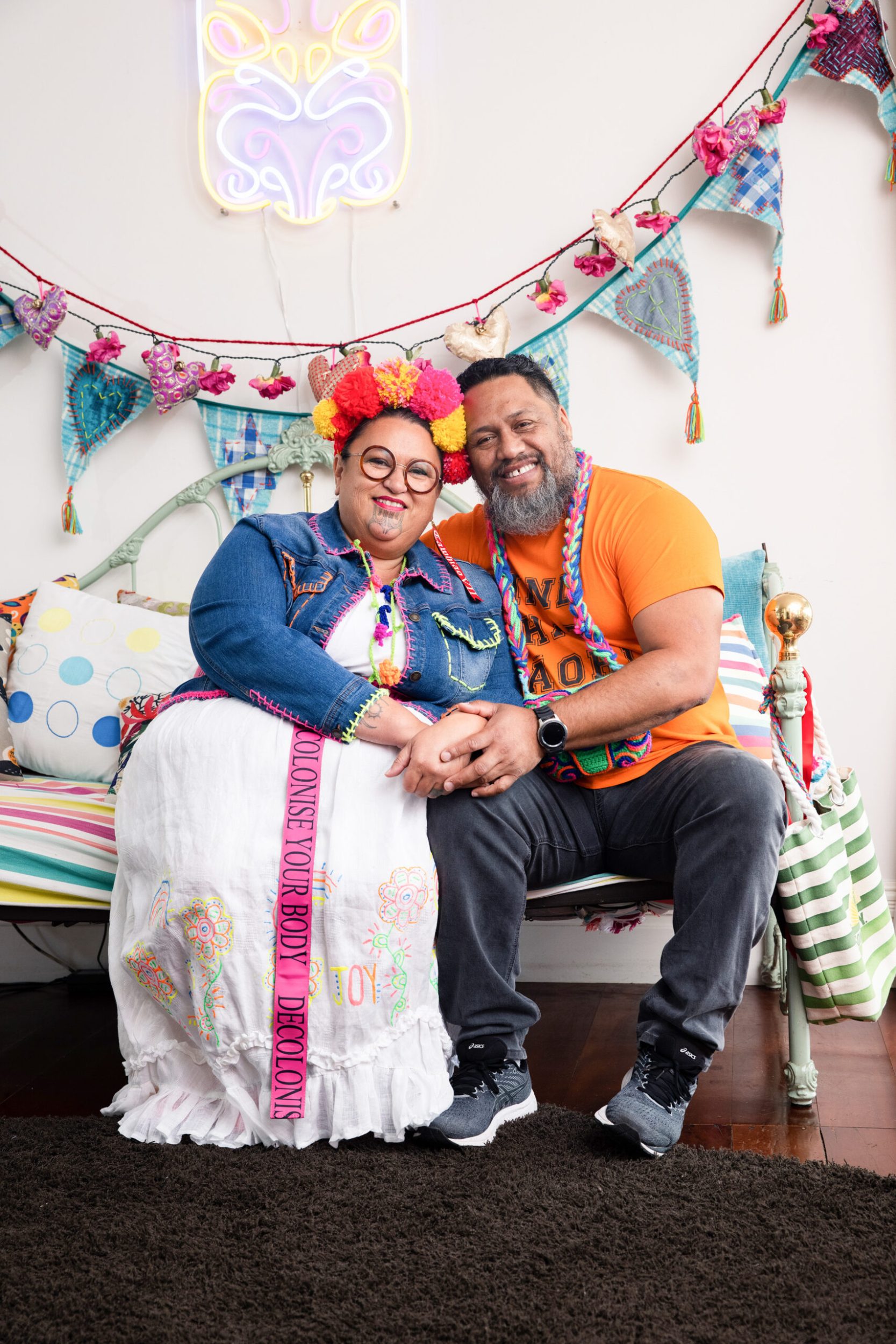 Lissy Robinson-Cole and husband Rudi sitting on couch together smiling and holding hands