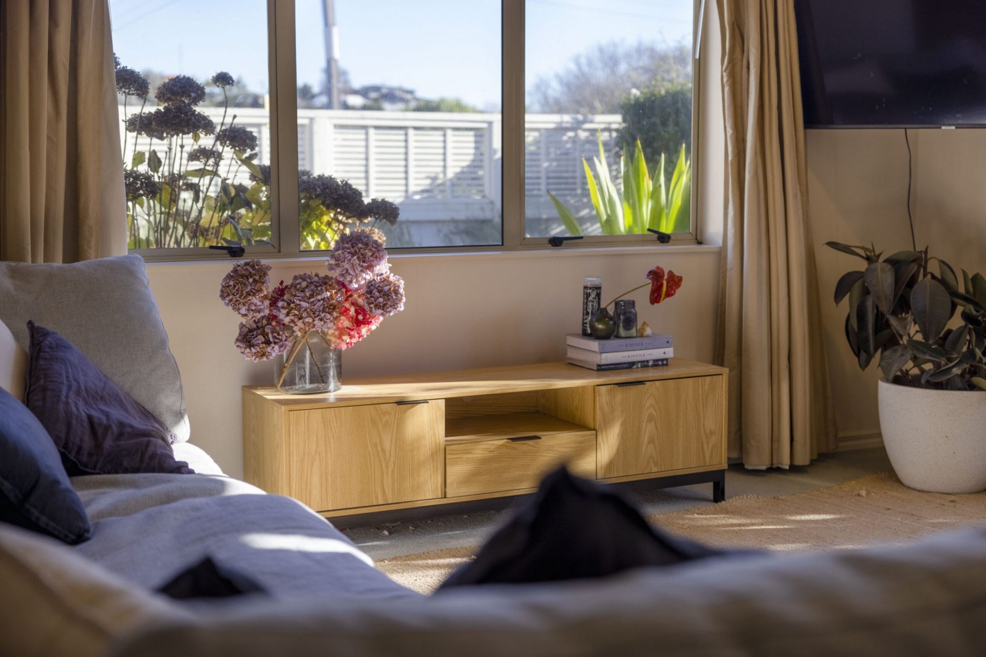 Living room with a small brown dresser with purple flowers on top