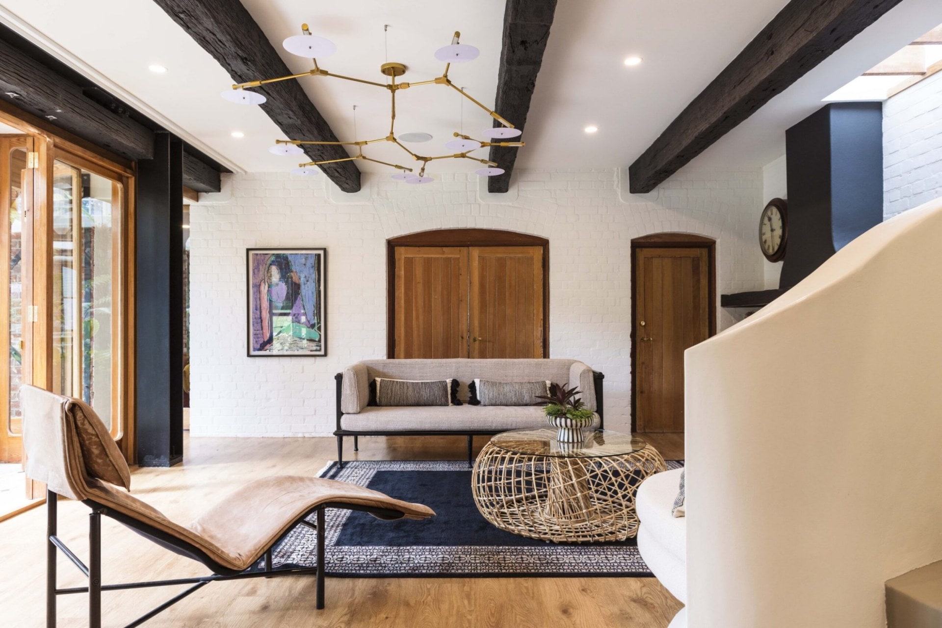 A white brick lounge with large wooden doors and gold hanging lights