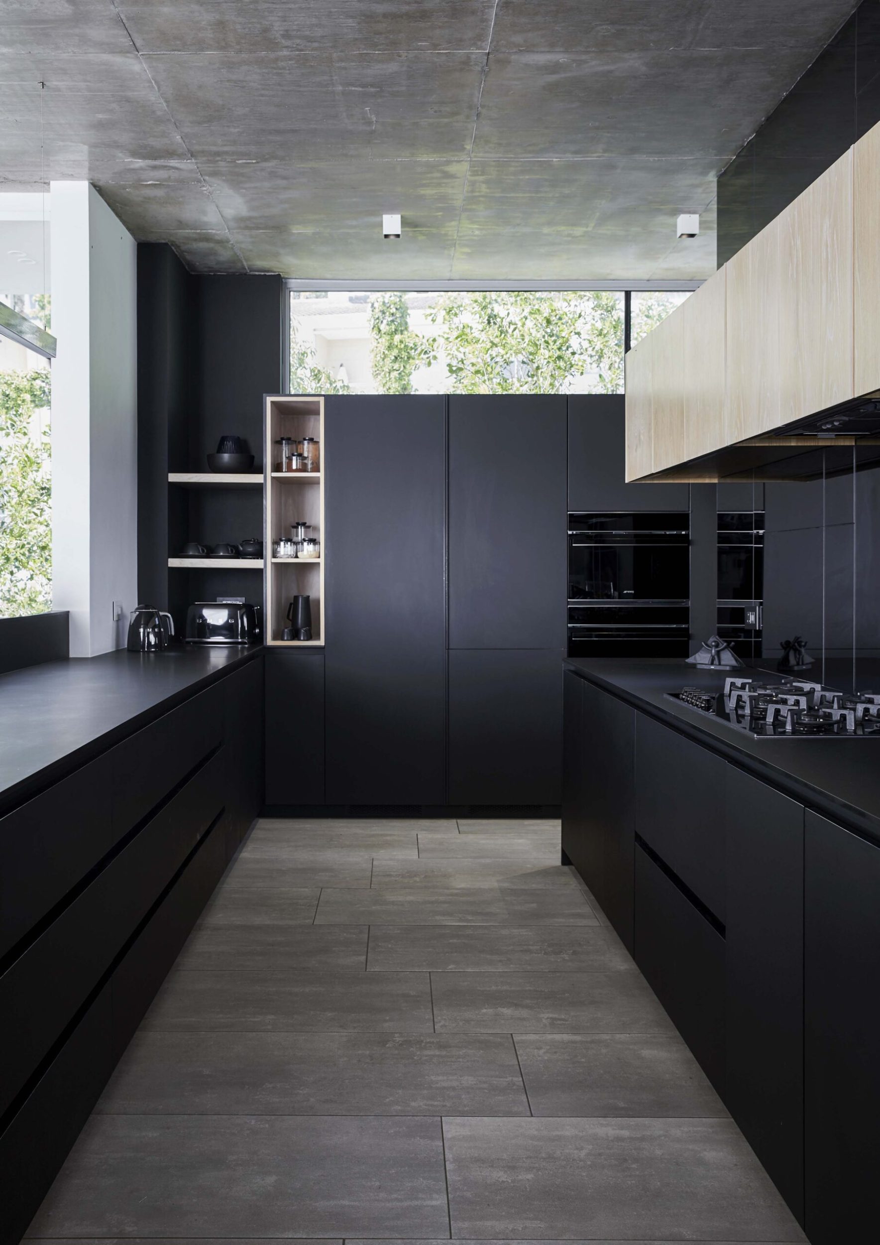 A black kitchen with light wood floors