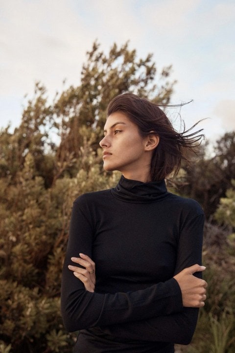 Woman wearing black turtleneck top looking out into the distance