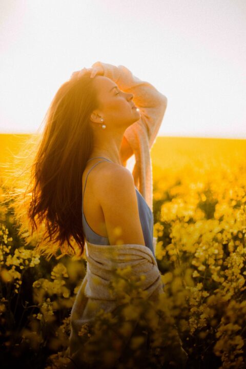 Woman standing in a field with her head tipped back and long hair
