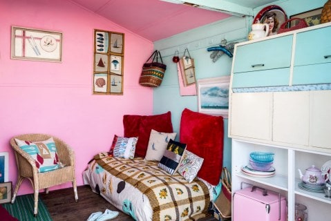 Pink and blue painted bedroom with an assortment of second-hand decor items, furniture and plates